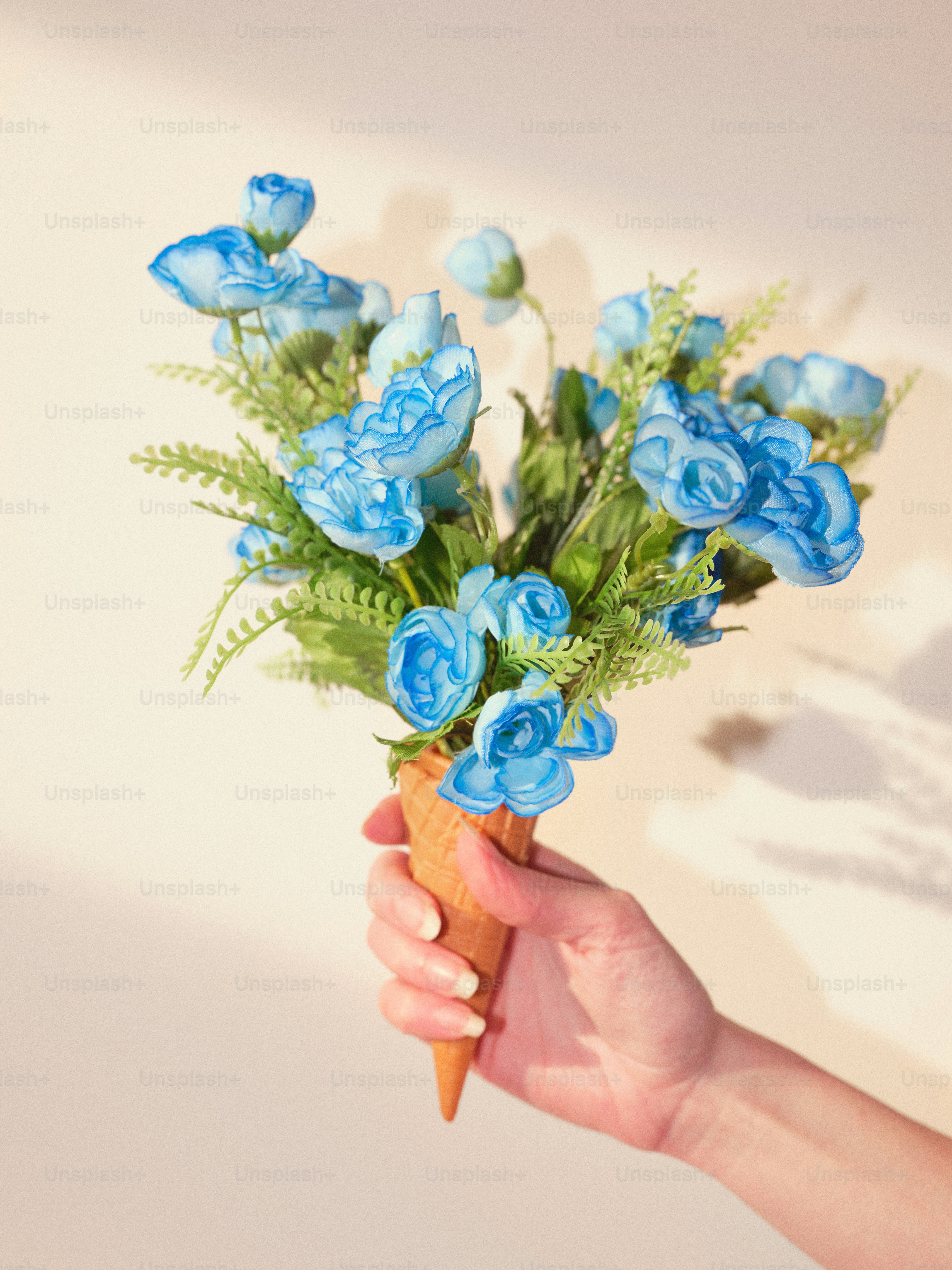 アイスクリームコーンに花束を挟んだ手。