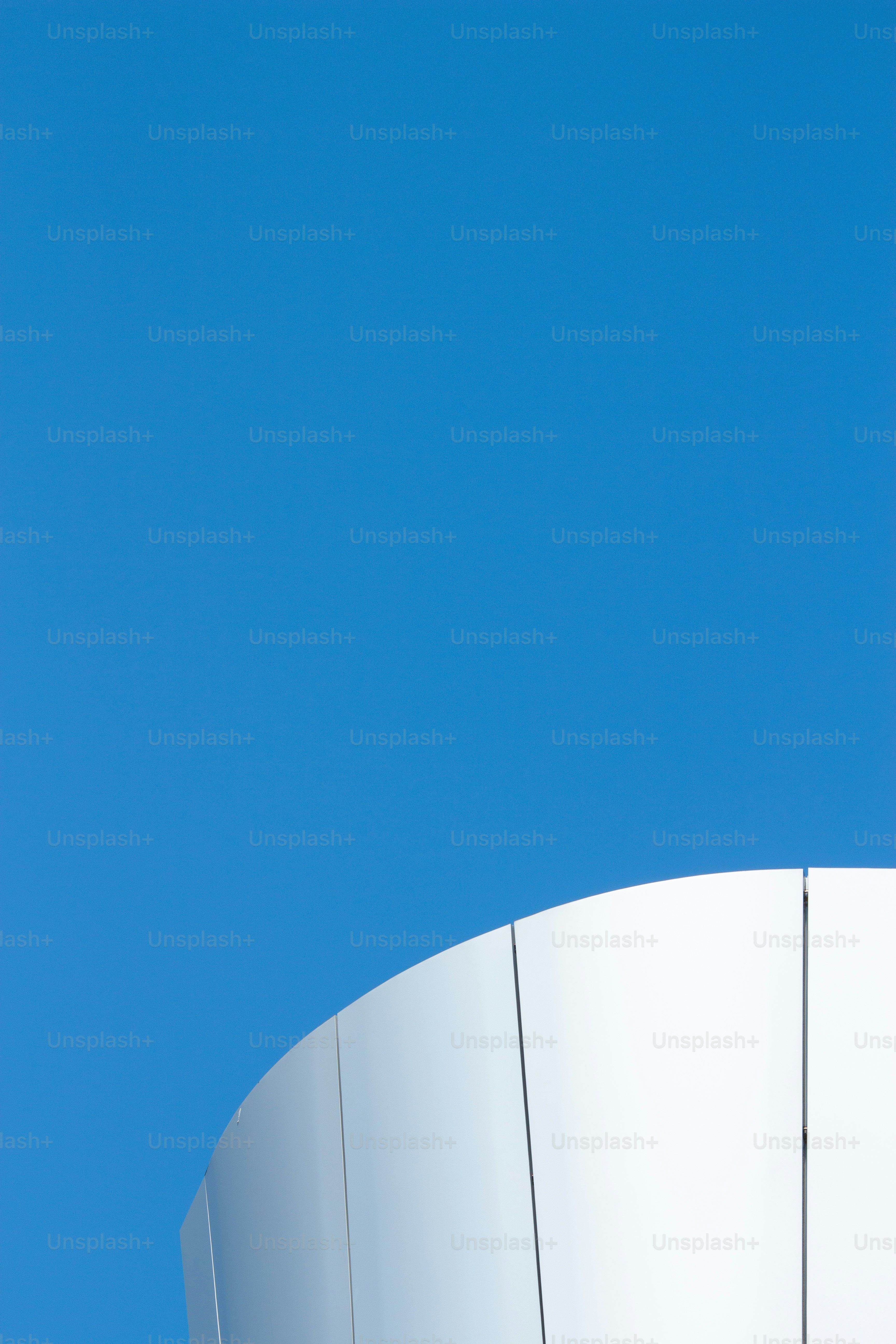 White curved building against a blue sky.