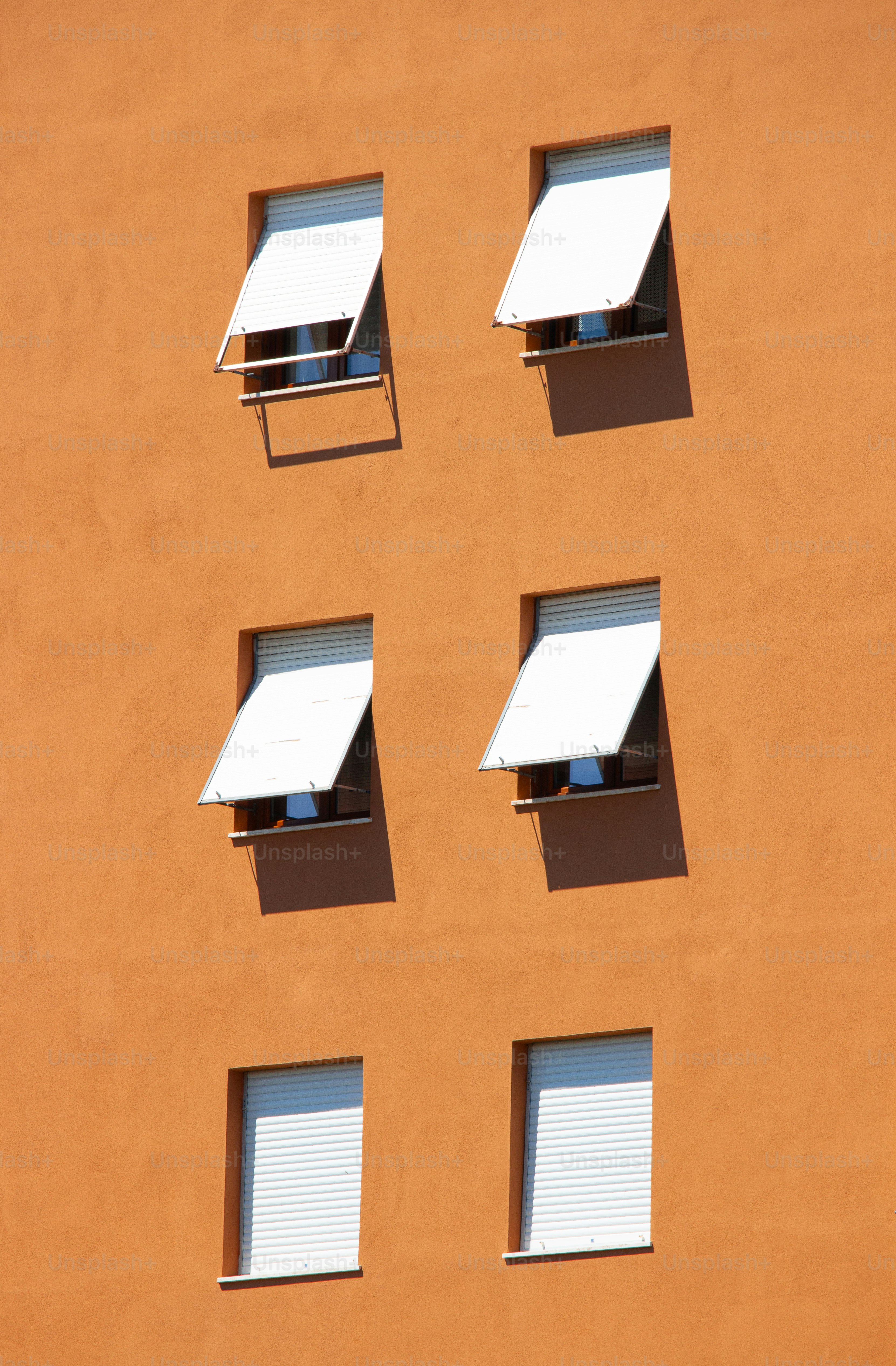 Windows with white awnings on an orange building.