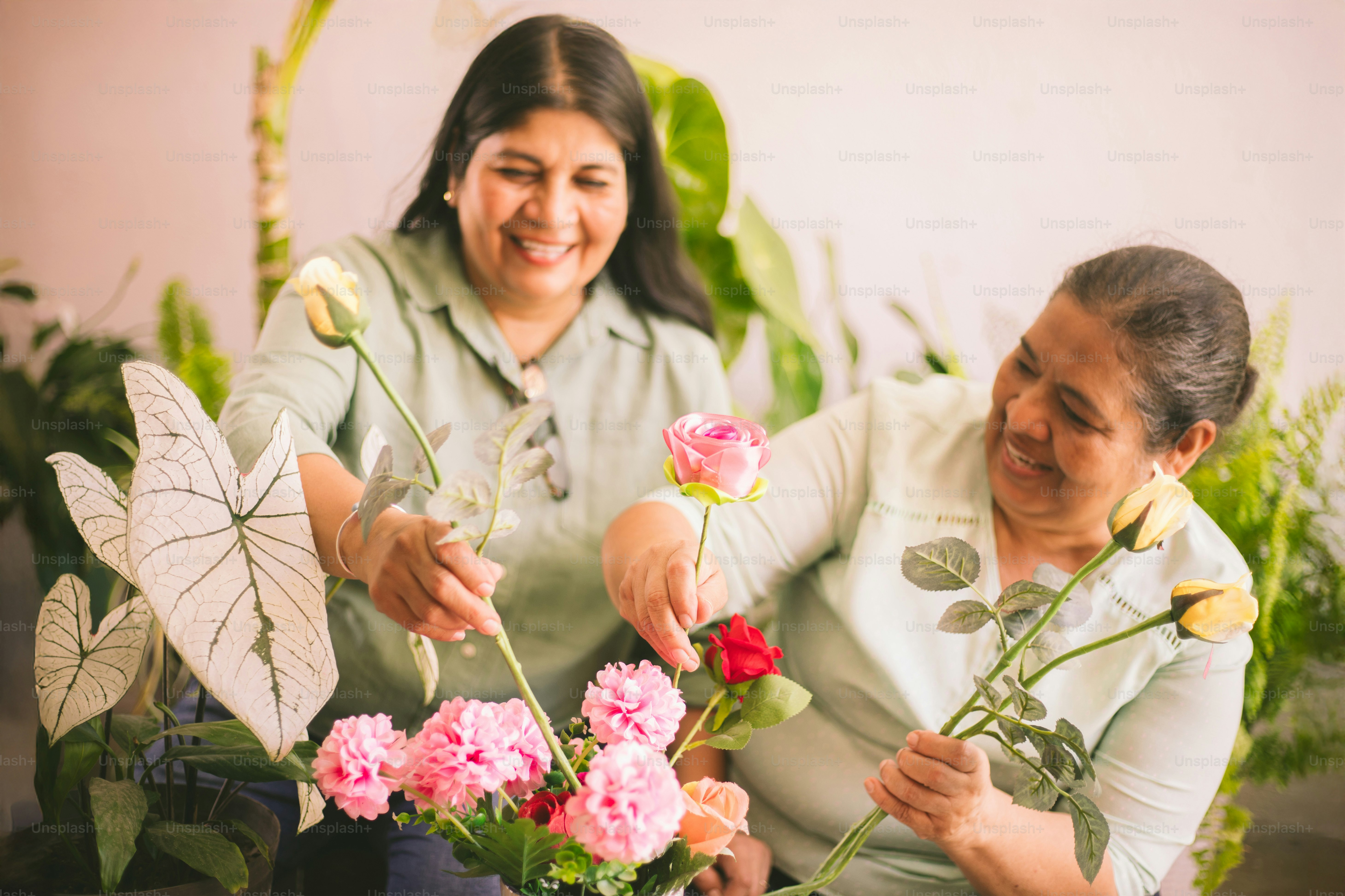 Two women arrange flowers together happily. photo – Roses Image on Unsplash
