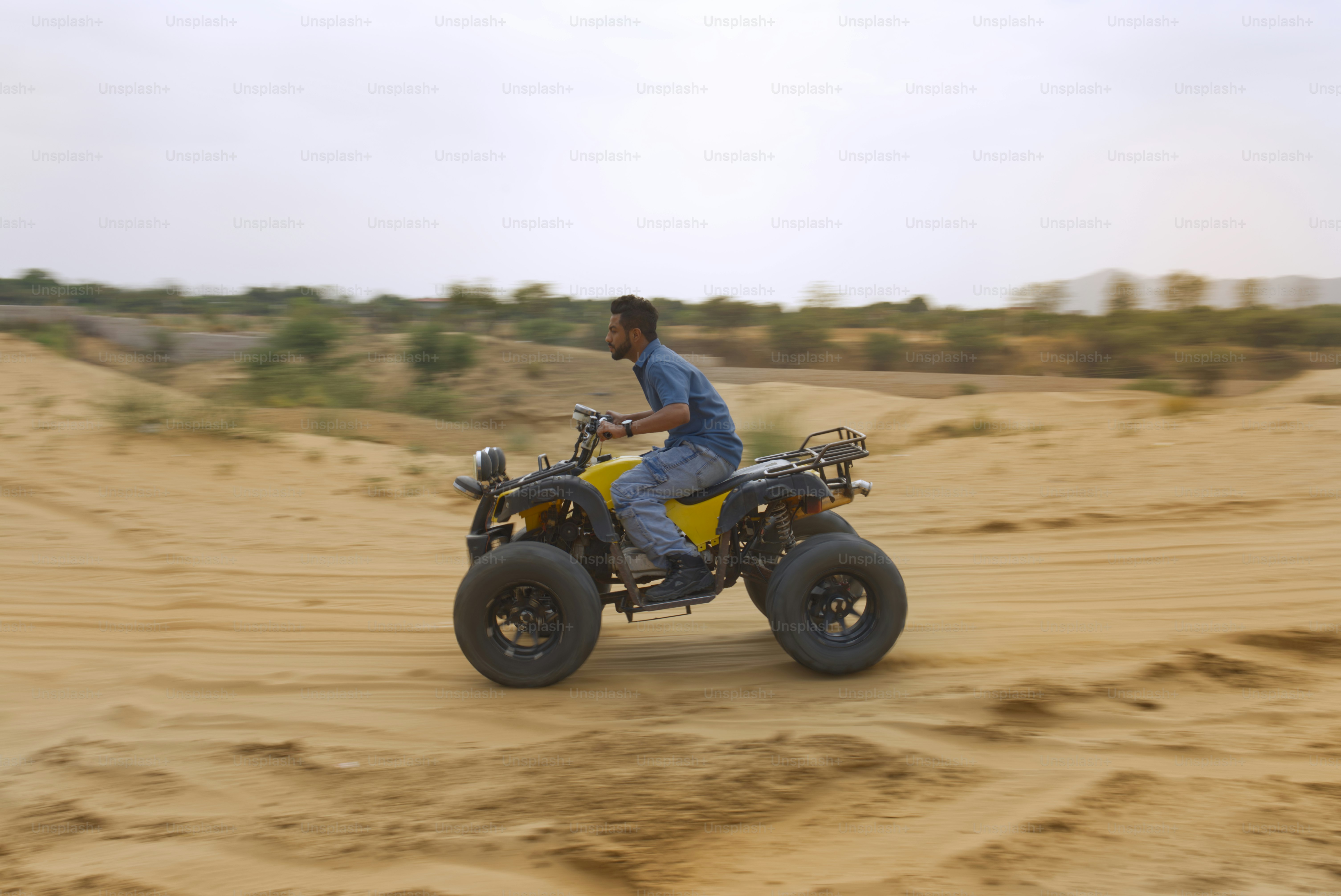 Man rides an atv through a sandy desert.