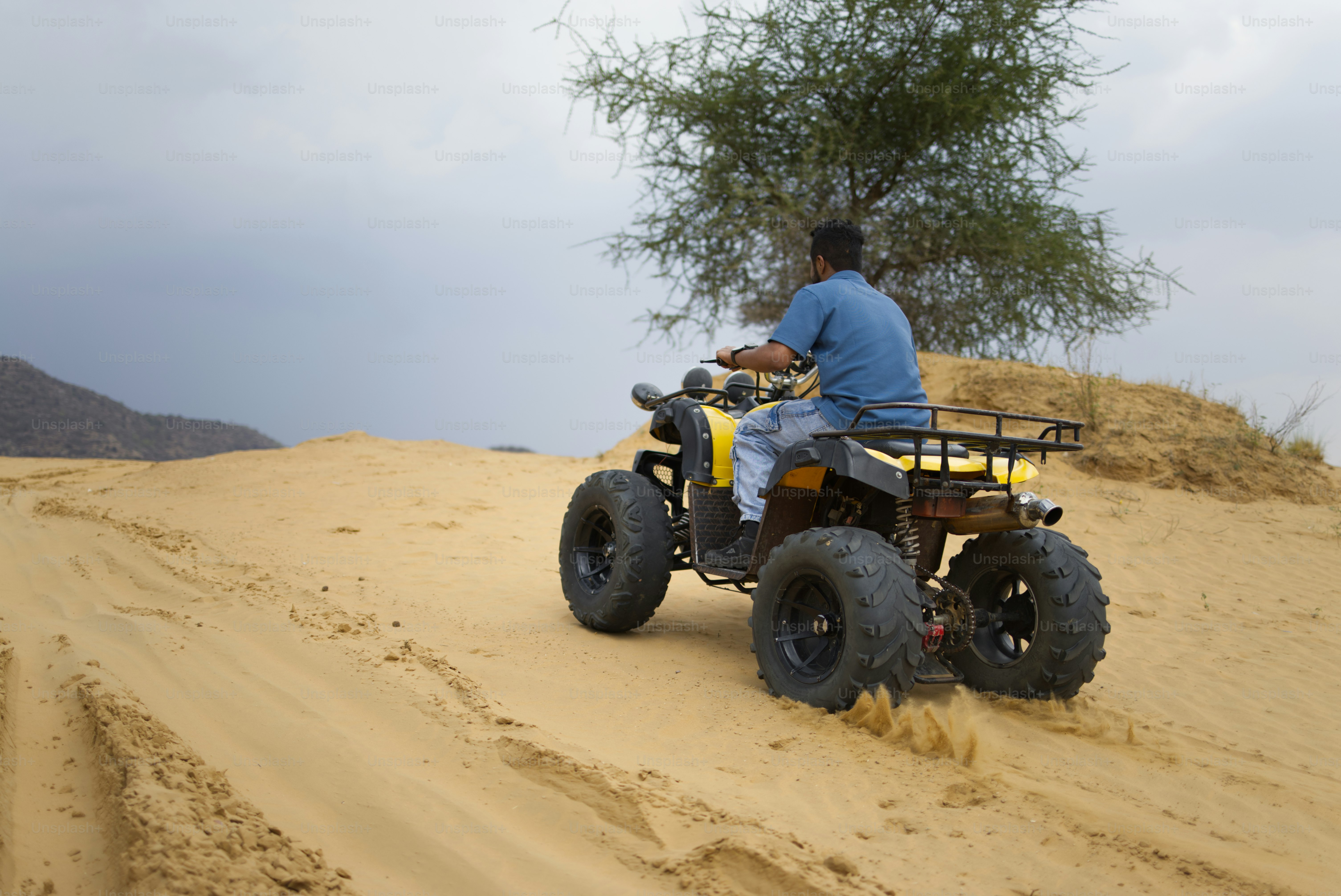 A person rides an atv through sandy terrain.