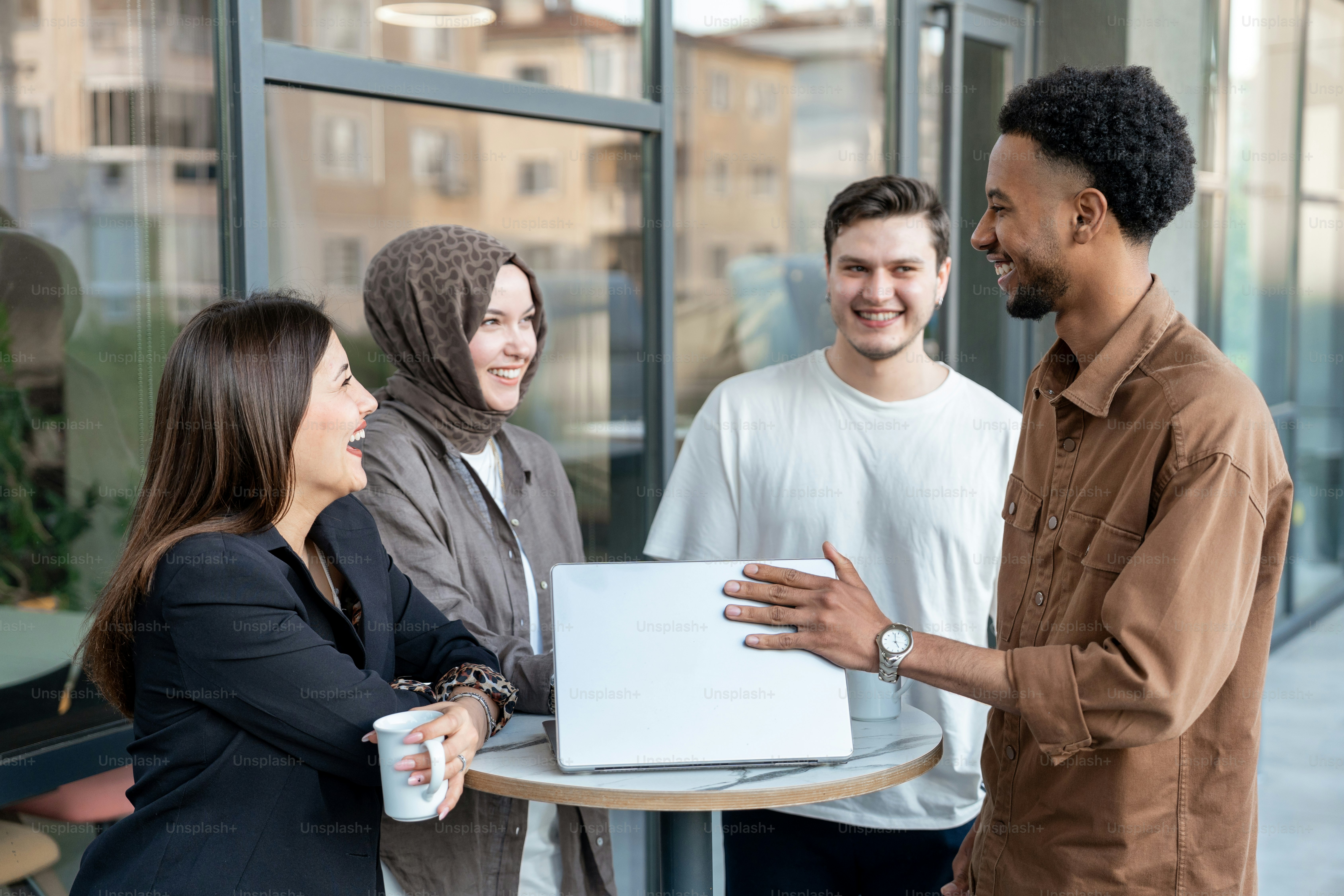 Vier Kollegen arbeiten zusammen, lächeln und reden miteinander.