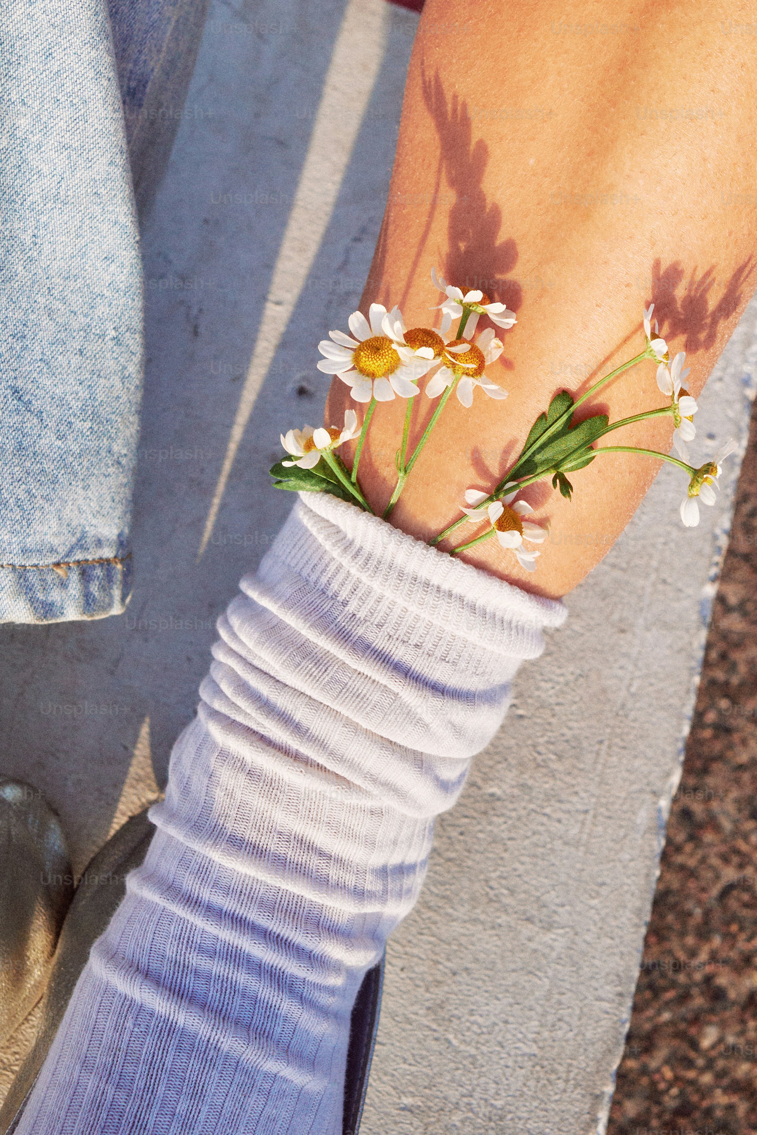 Blumen lugen aus einer weißen Socke an einem Bein.