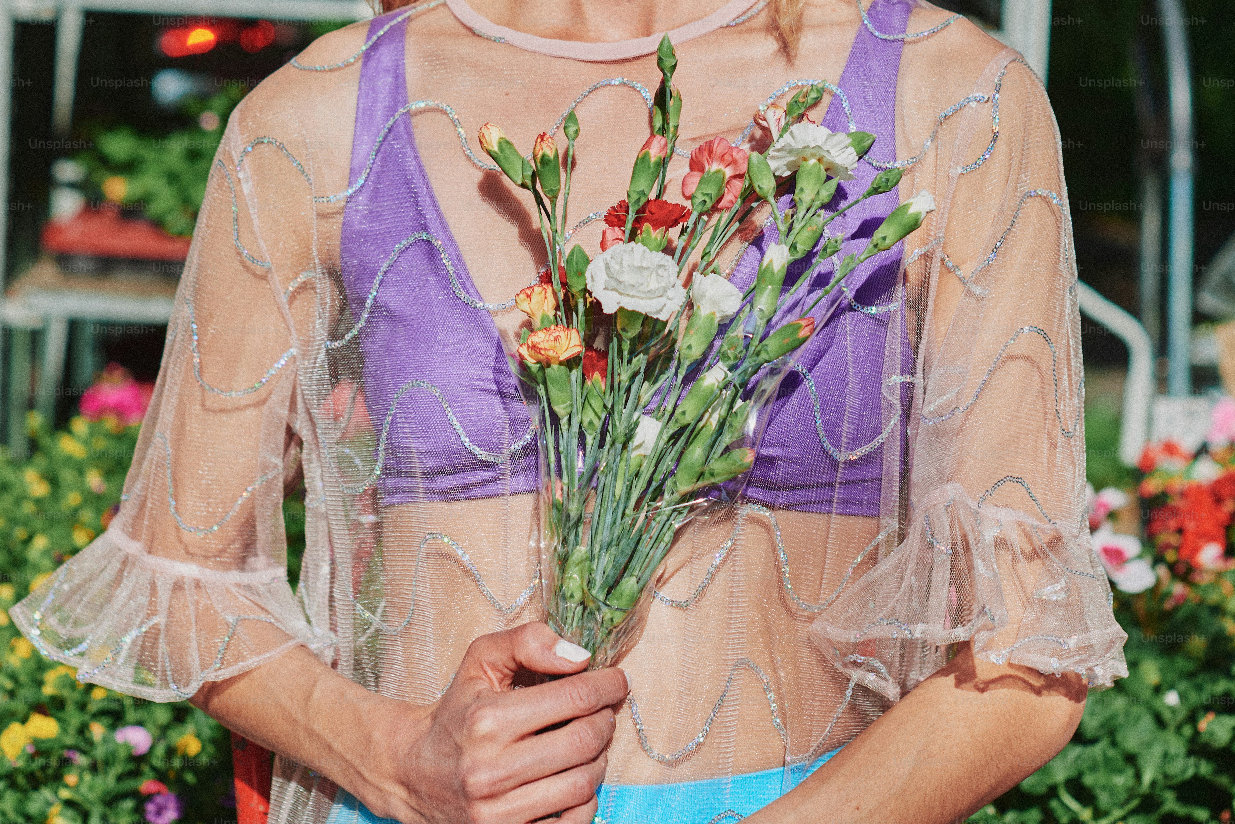 Frau hält Blumen in einem Gewächshaus.