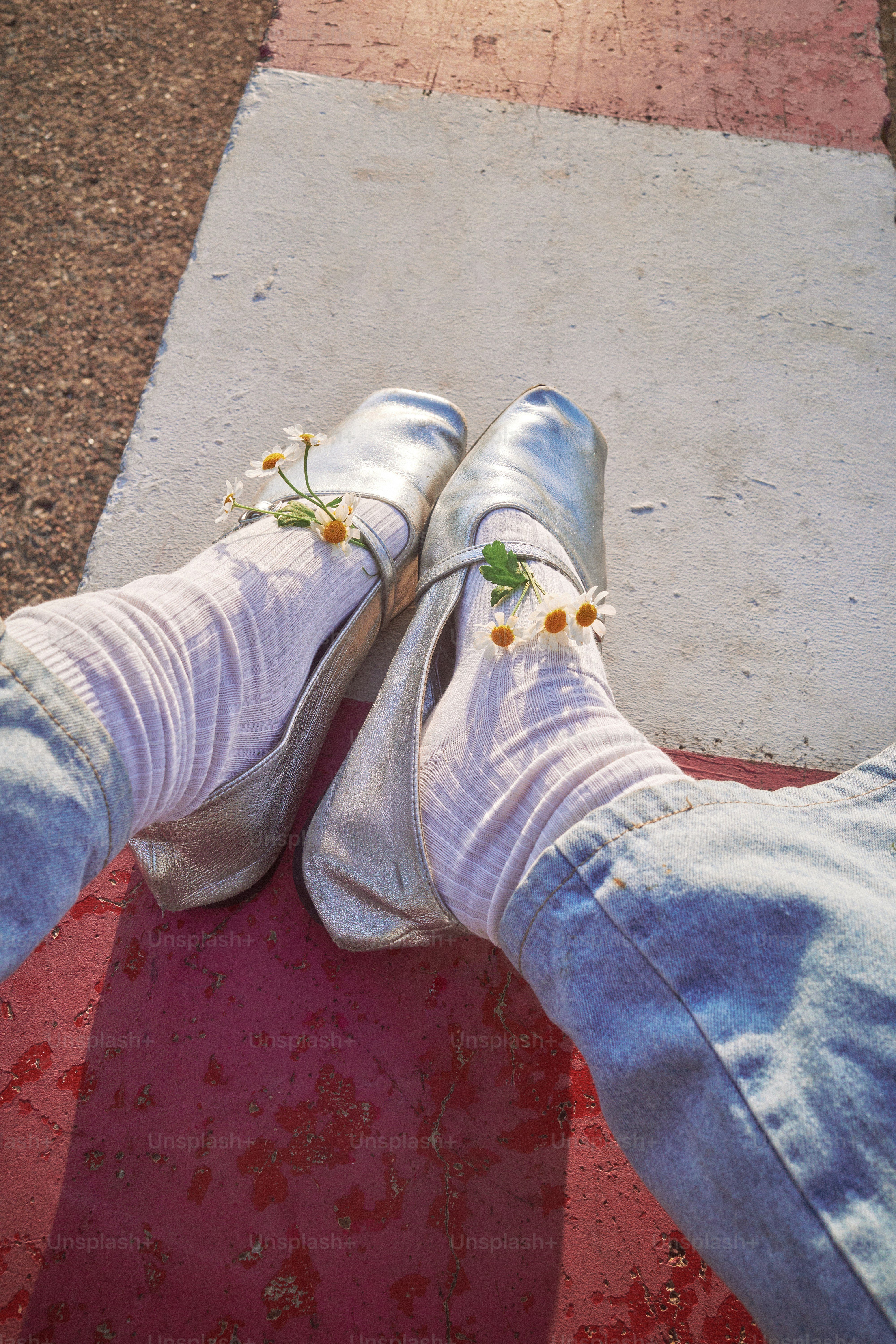Silberne Schuhe, die mit Gänseblümchen geschmückt sind, liegen auf einem Weg.
