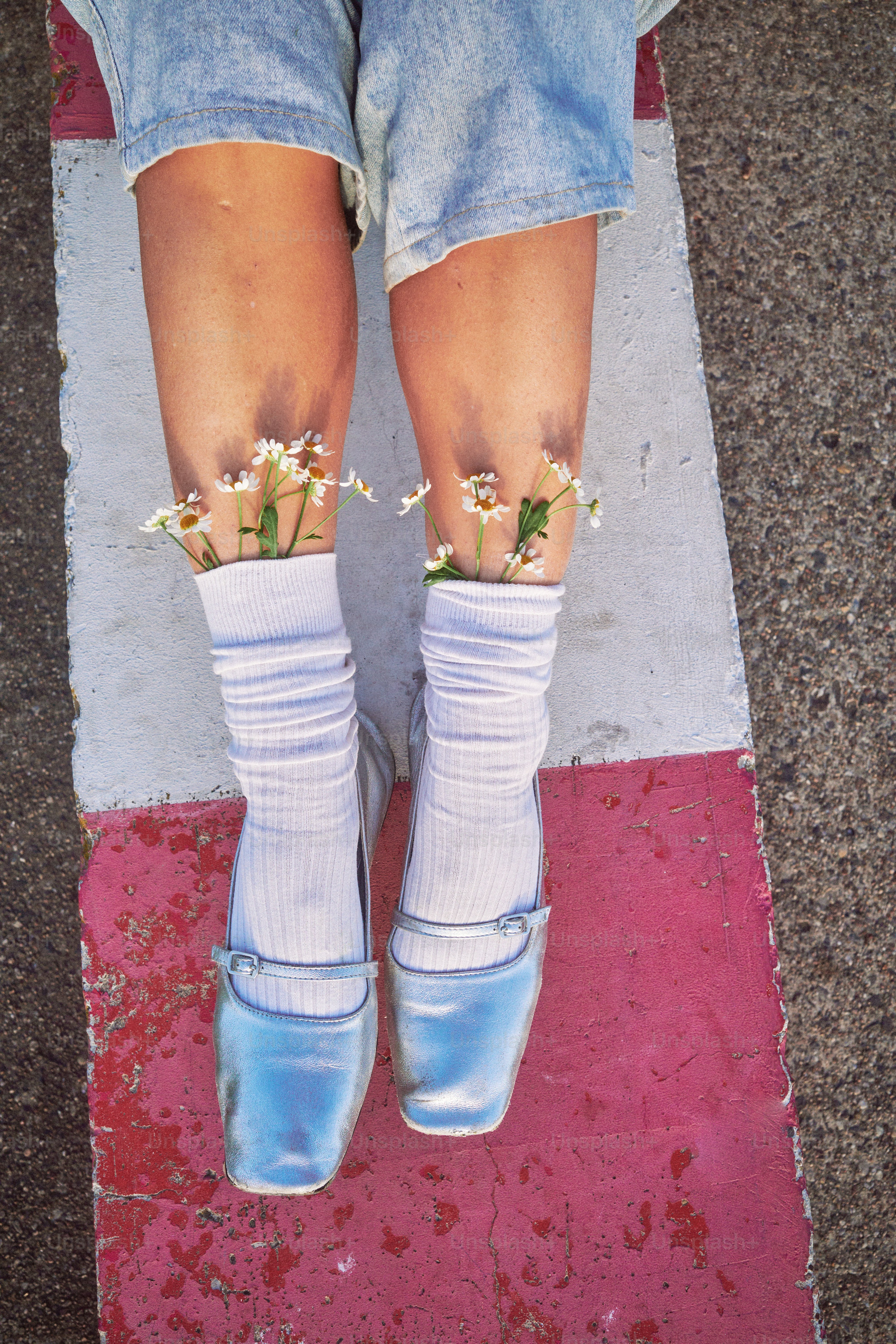 Pernas com flores em meias e sapatos prateados.