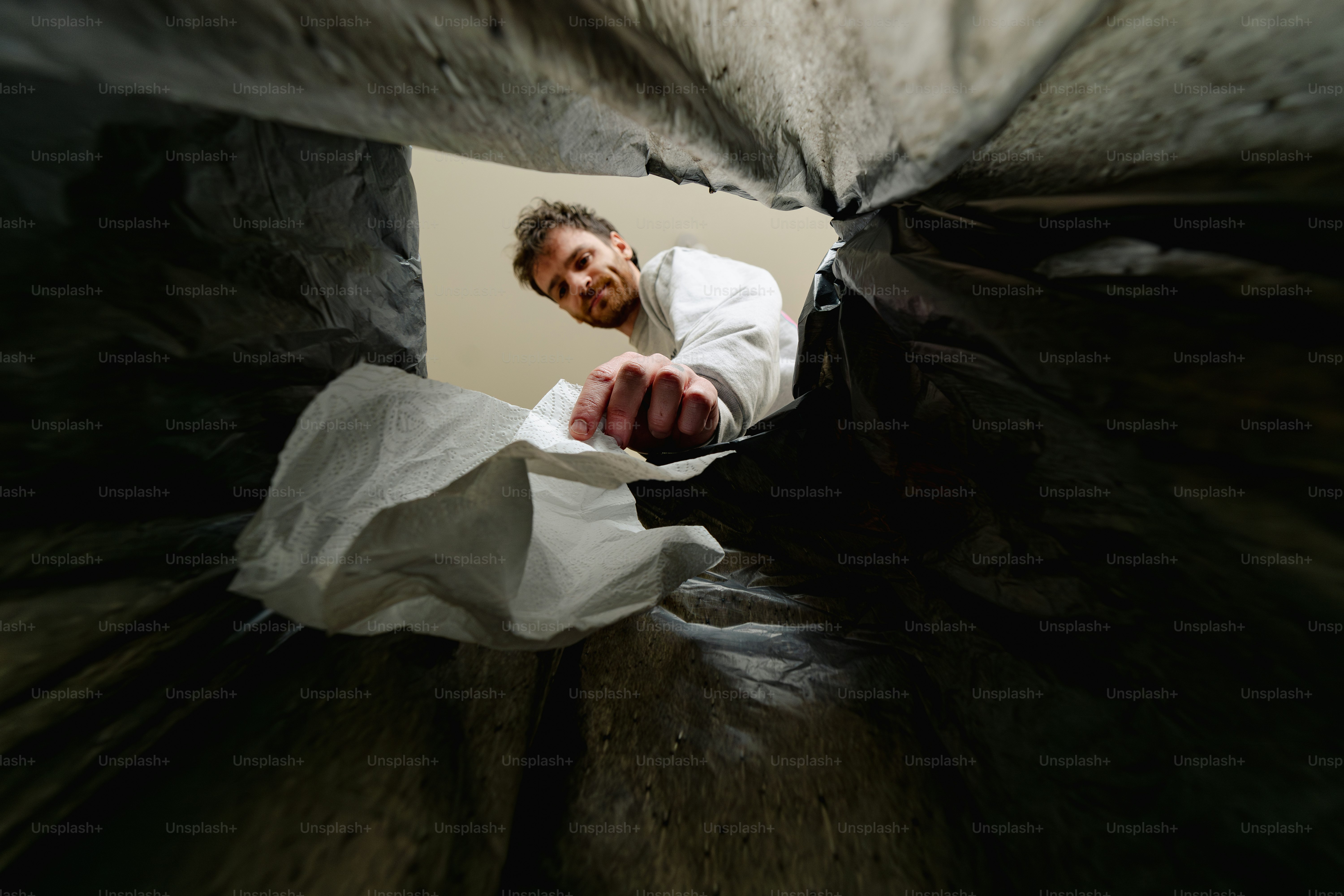 A person reaches into a dark trash bag.