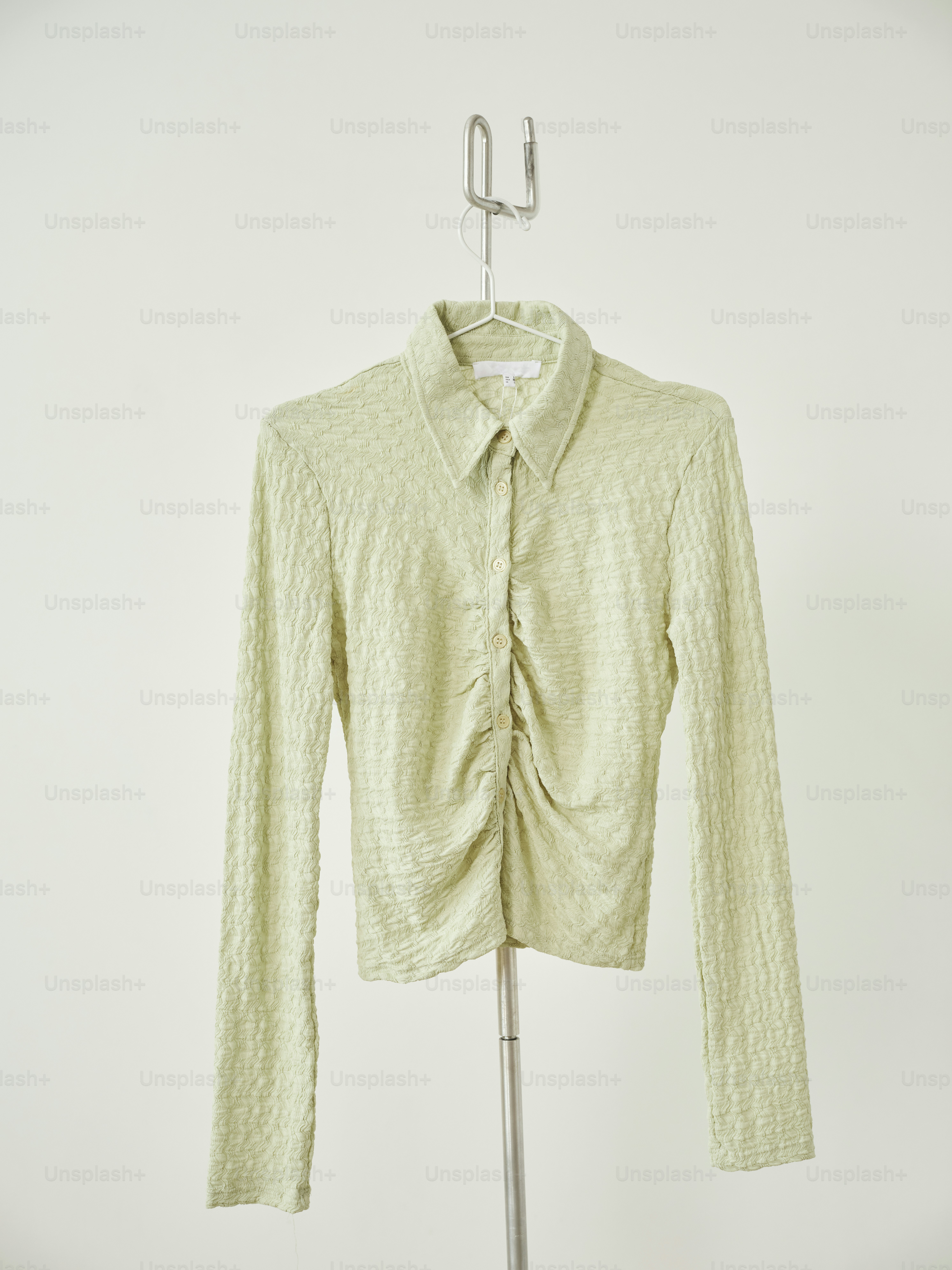 A green shirt hangs on a clothes rack.