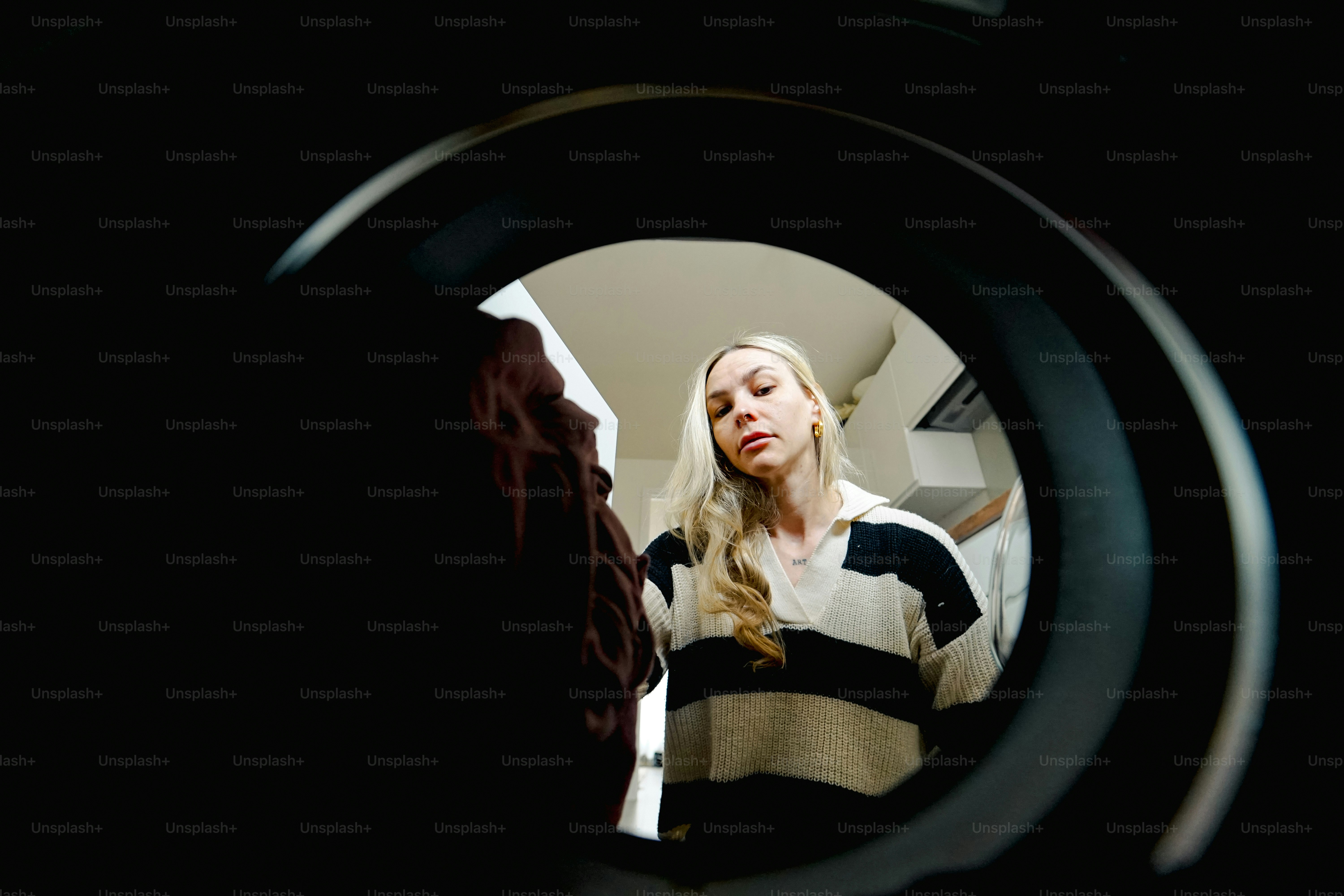 A woman looks inside a washing machine.