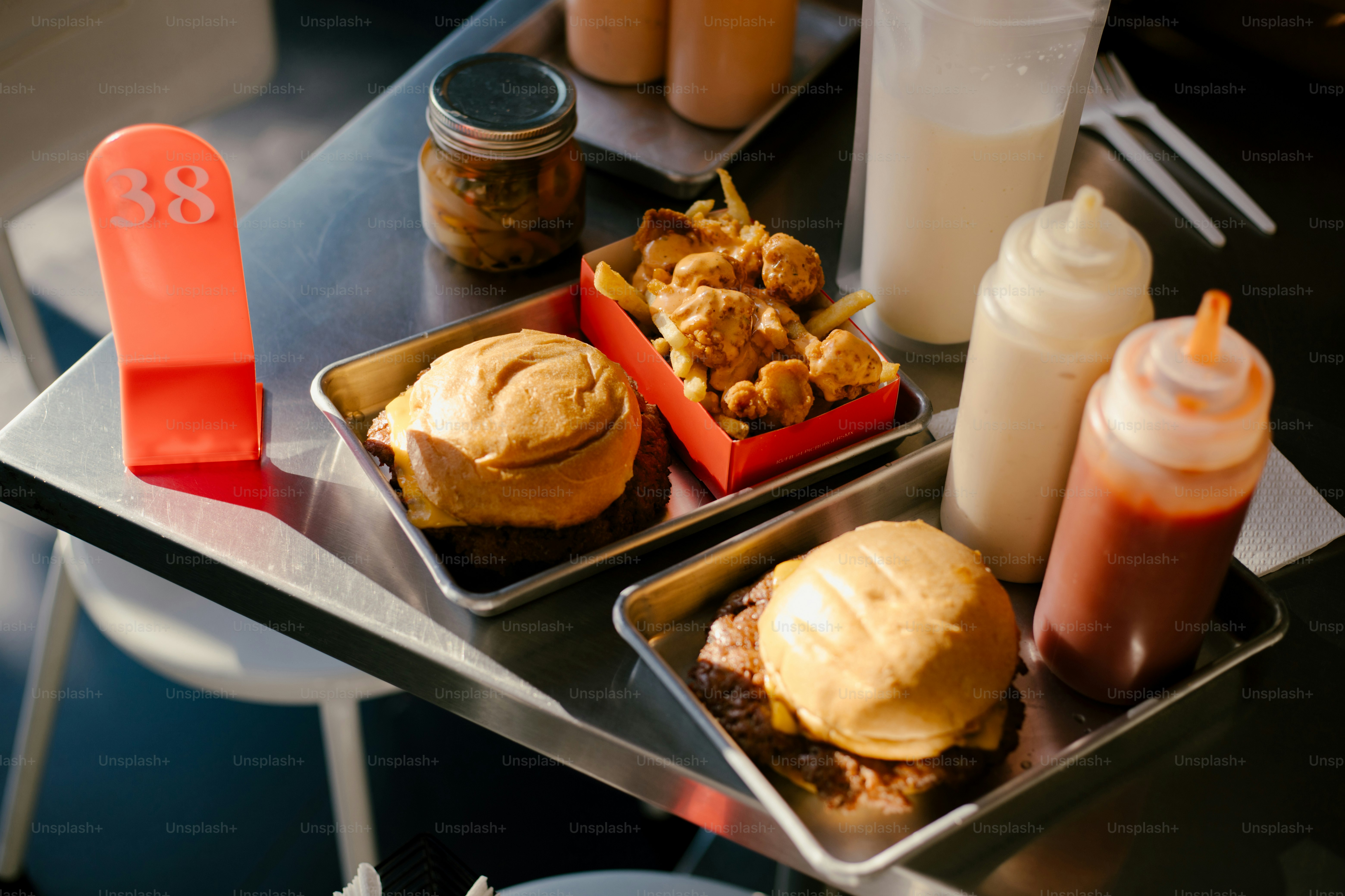Burgers, fries, sauces, and sides on a tray.