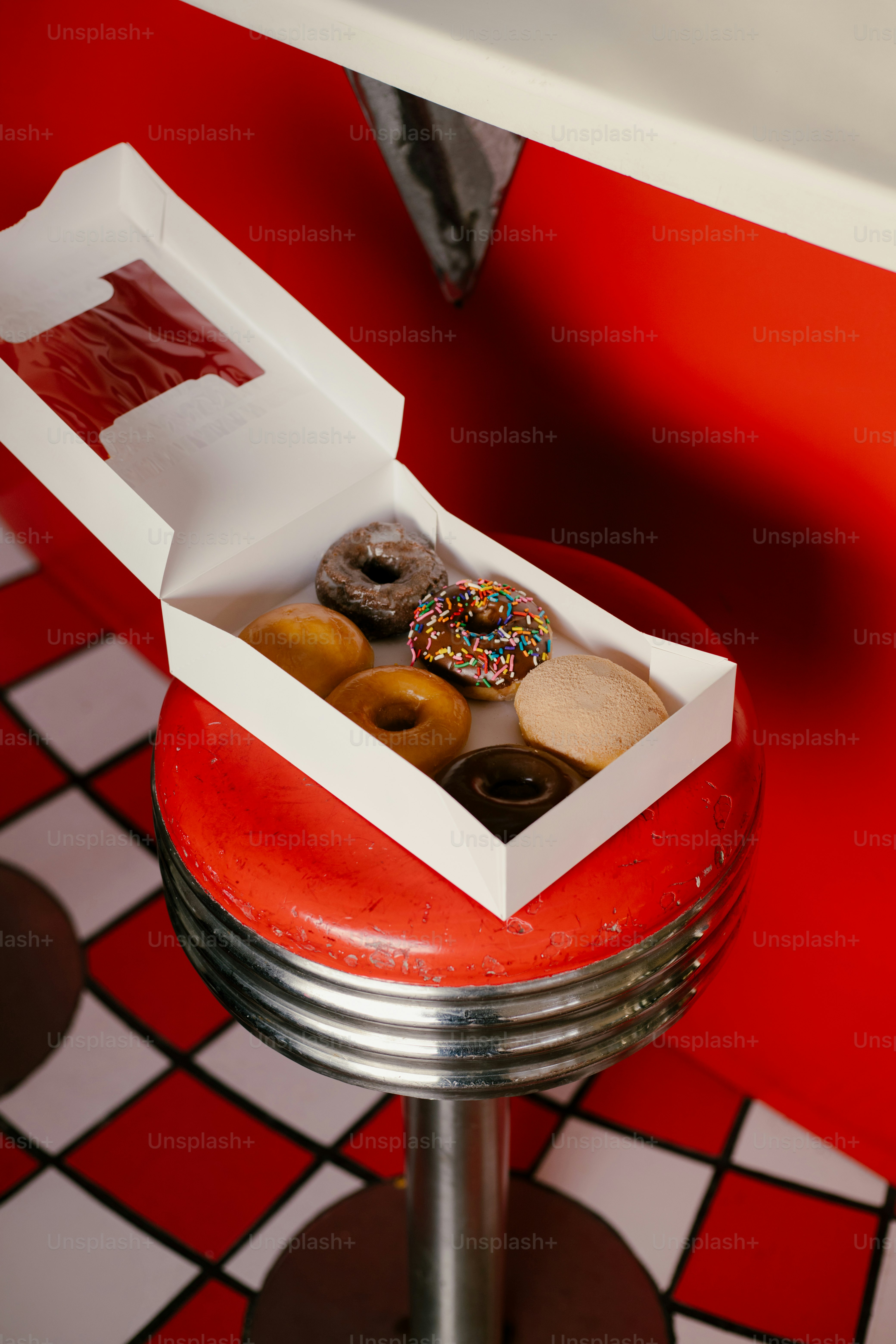 Eine Schachtel mit verschiedenen Donuts steht auf einem Hocker