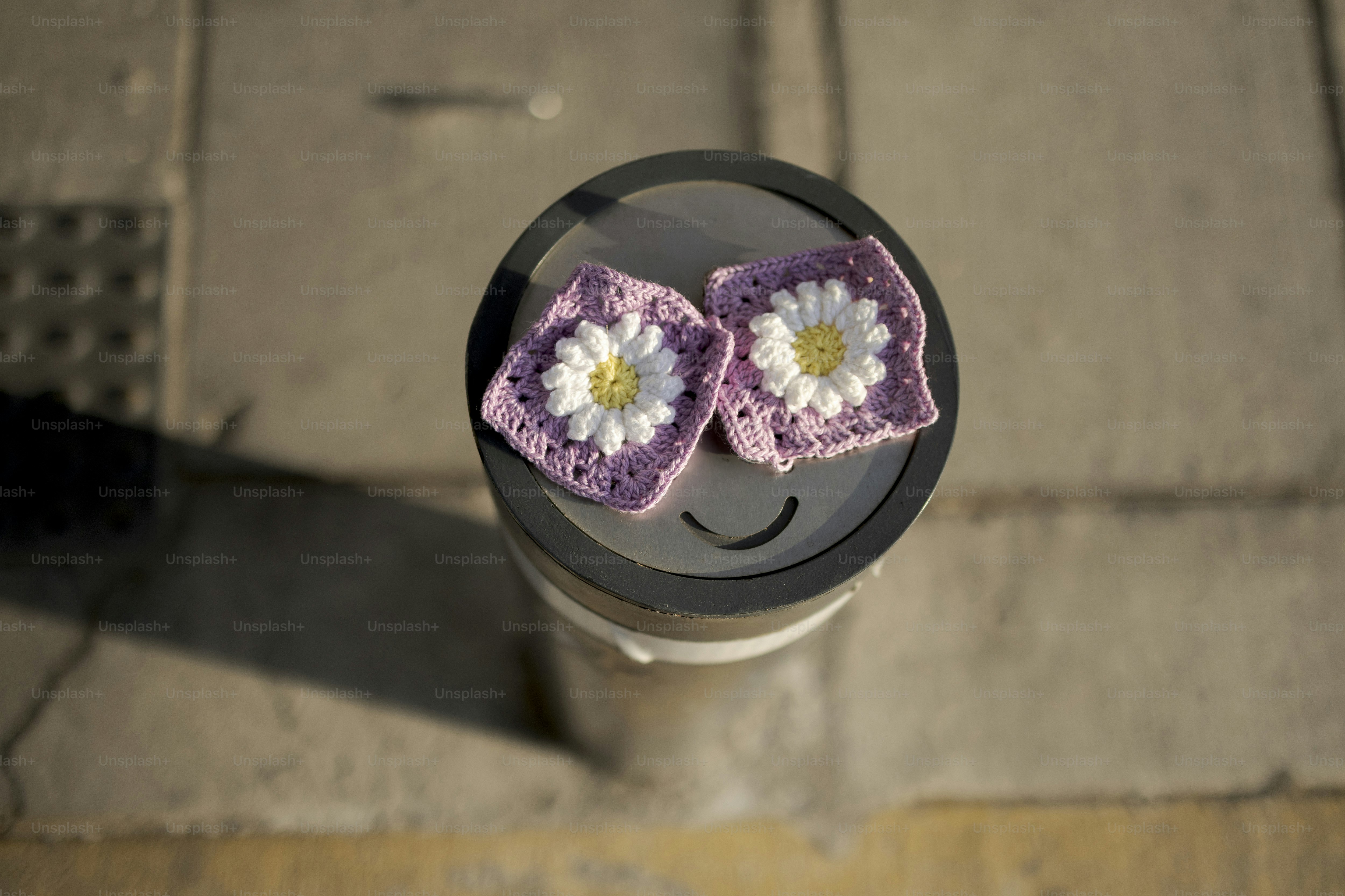 Les carrés de marguerites au crochet reposent sur un objet cylindrique.