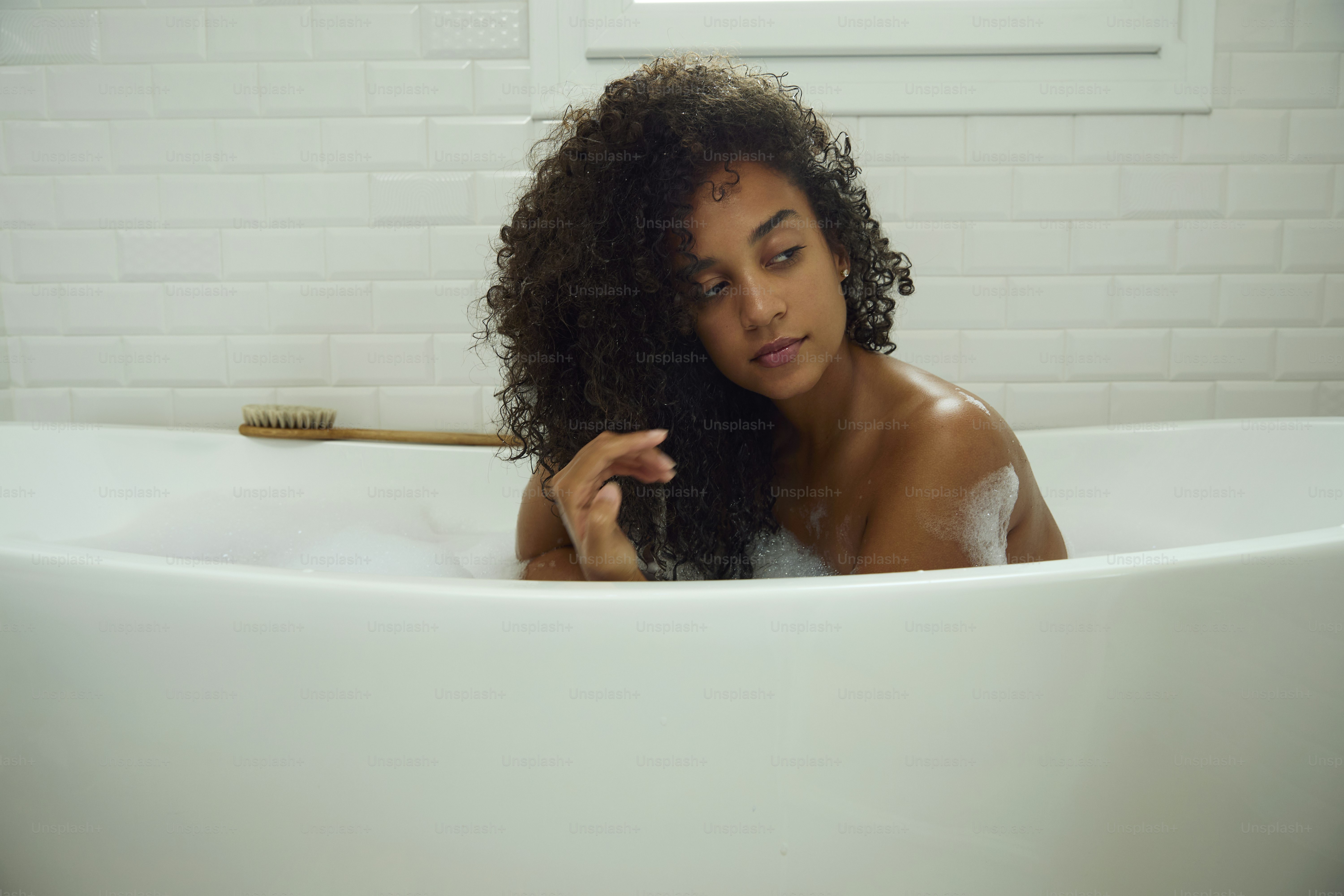Frau entspannt sich in einer Badewanne mit Wasser.