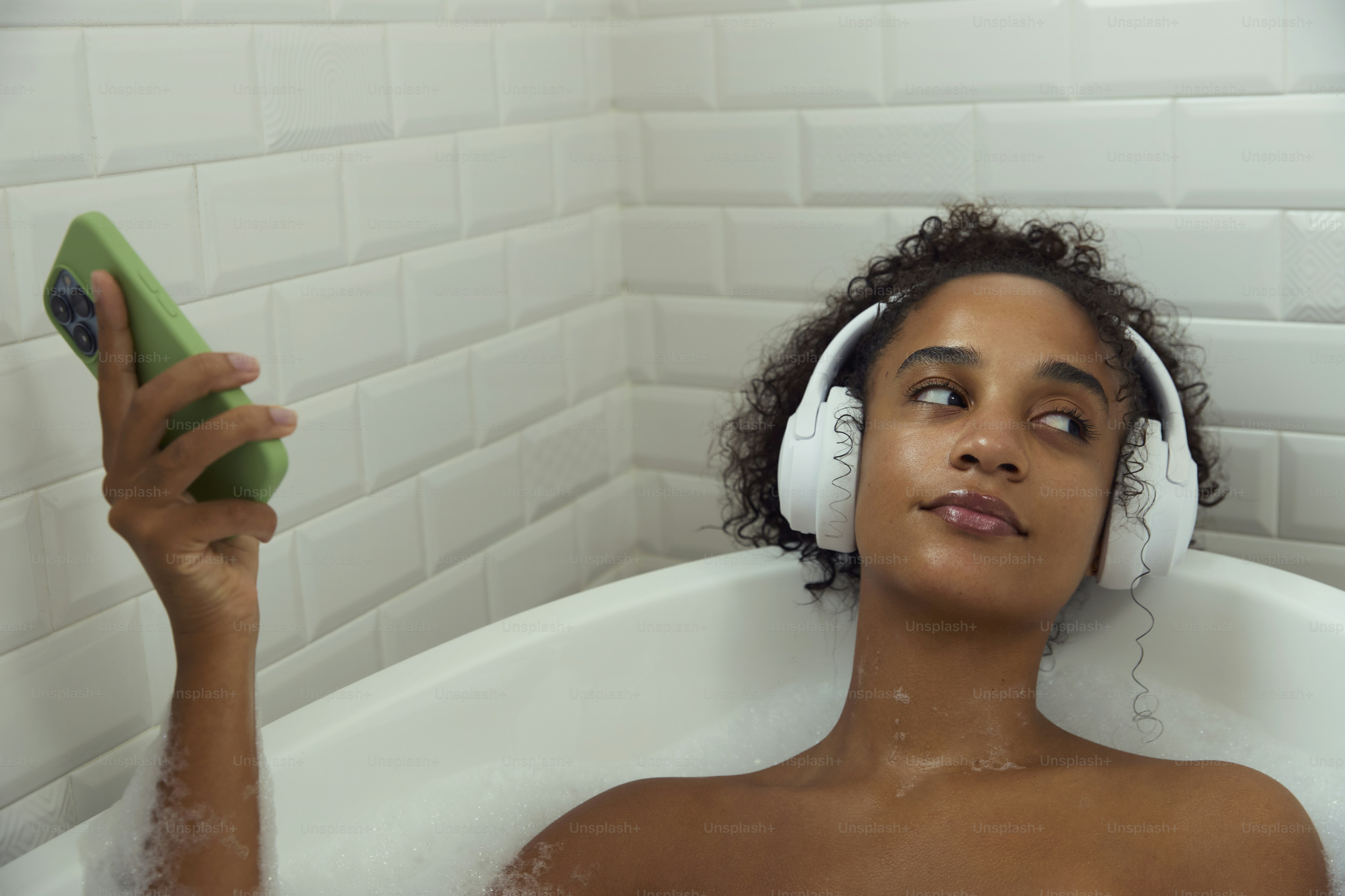 Frau entspannt sich in einer Wanne und hört Musik.