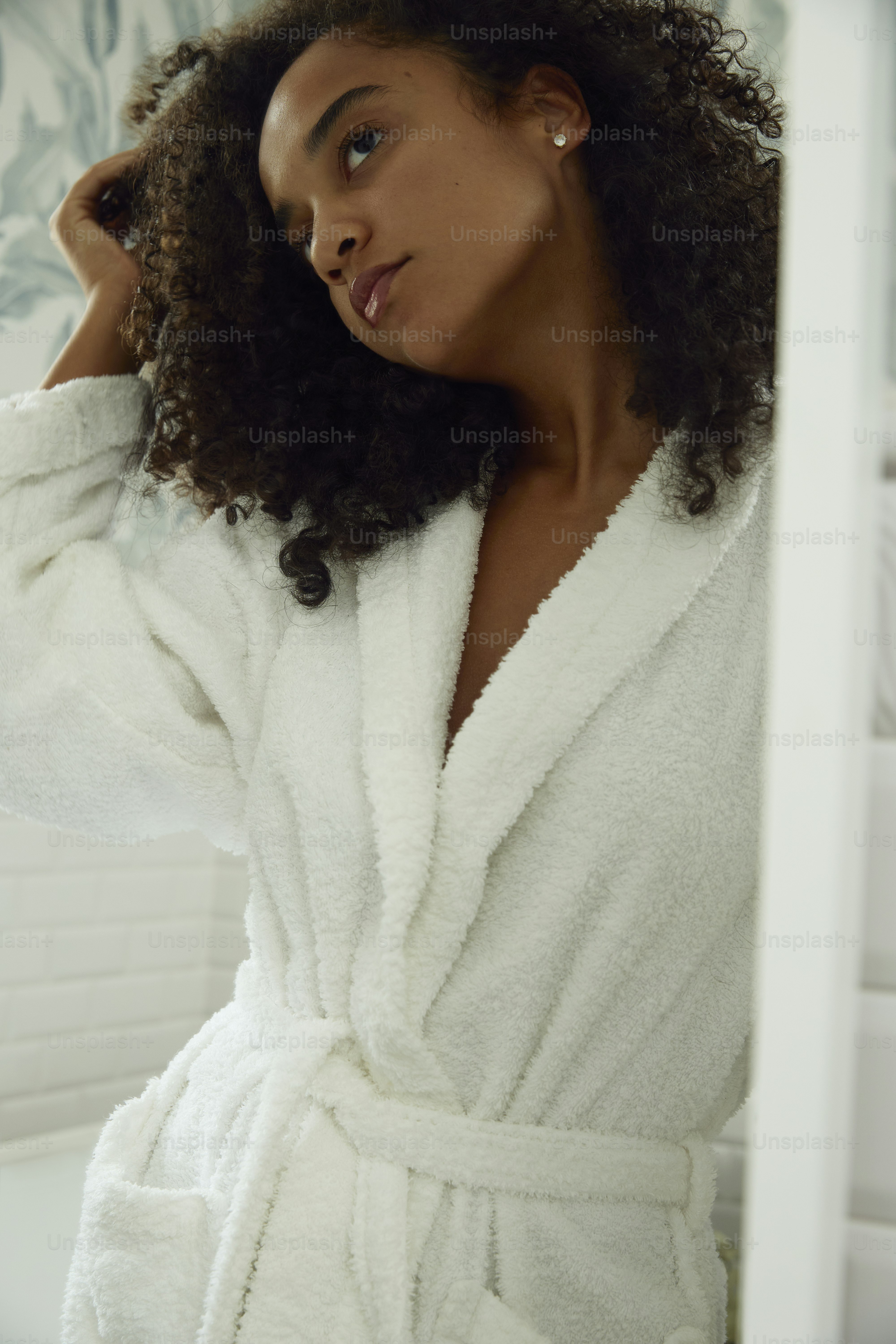 A woman in a robe is looking in a mirror.