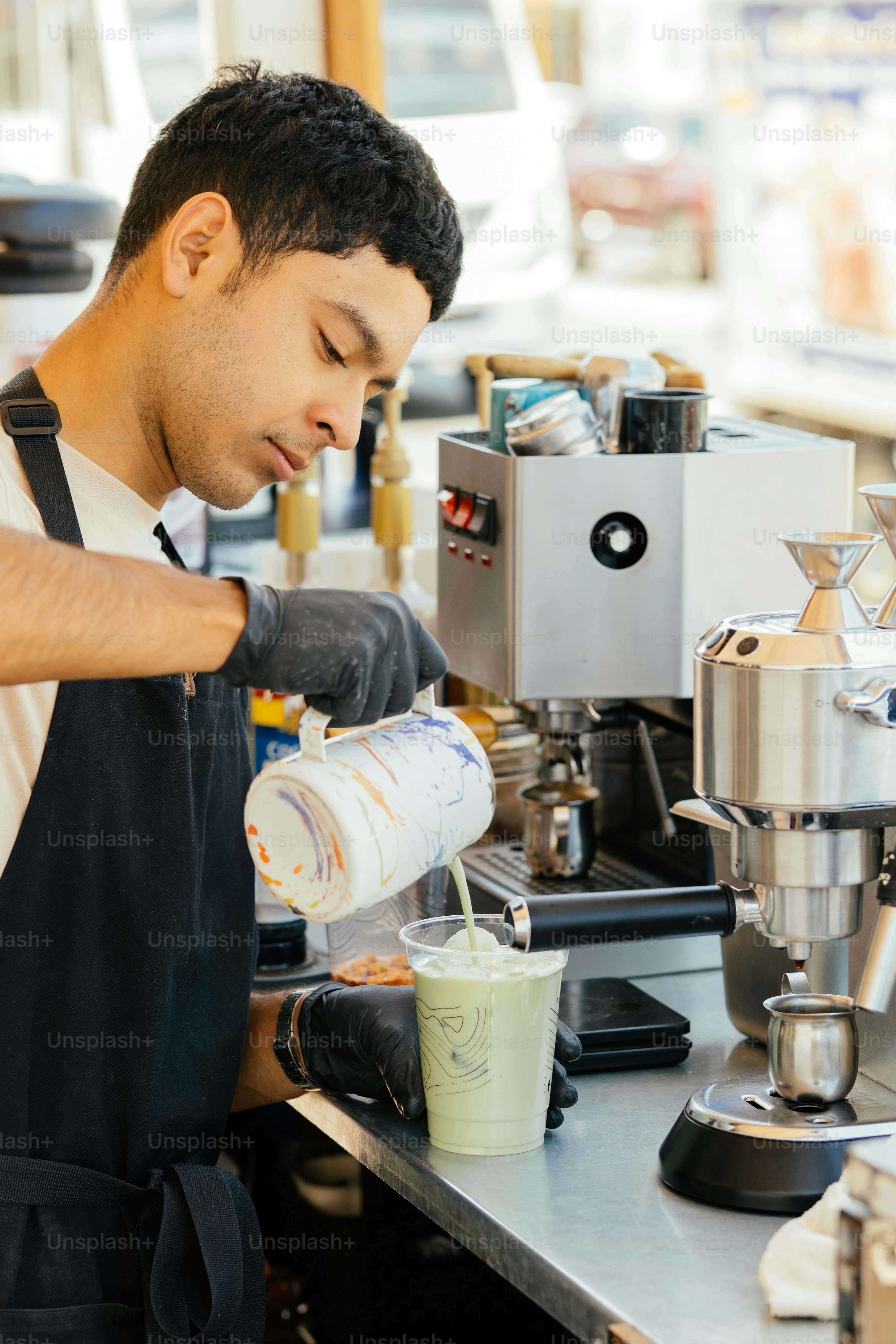 Barista menuangkan susu ke dalam minuman matcha.