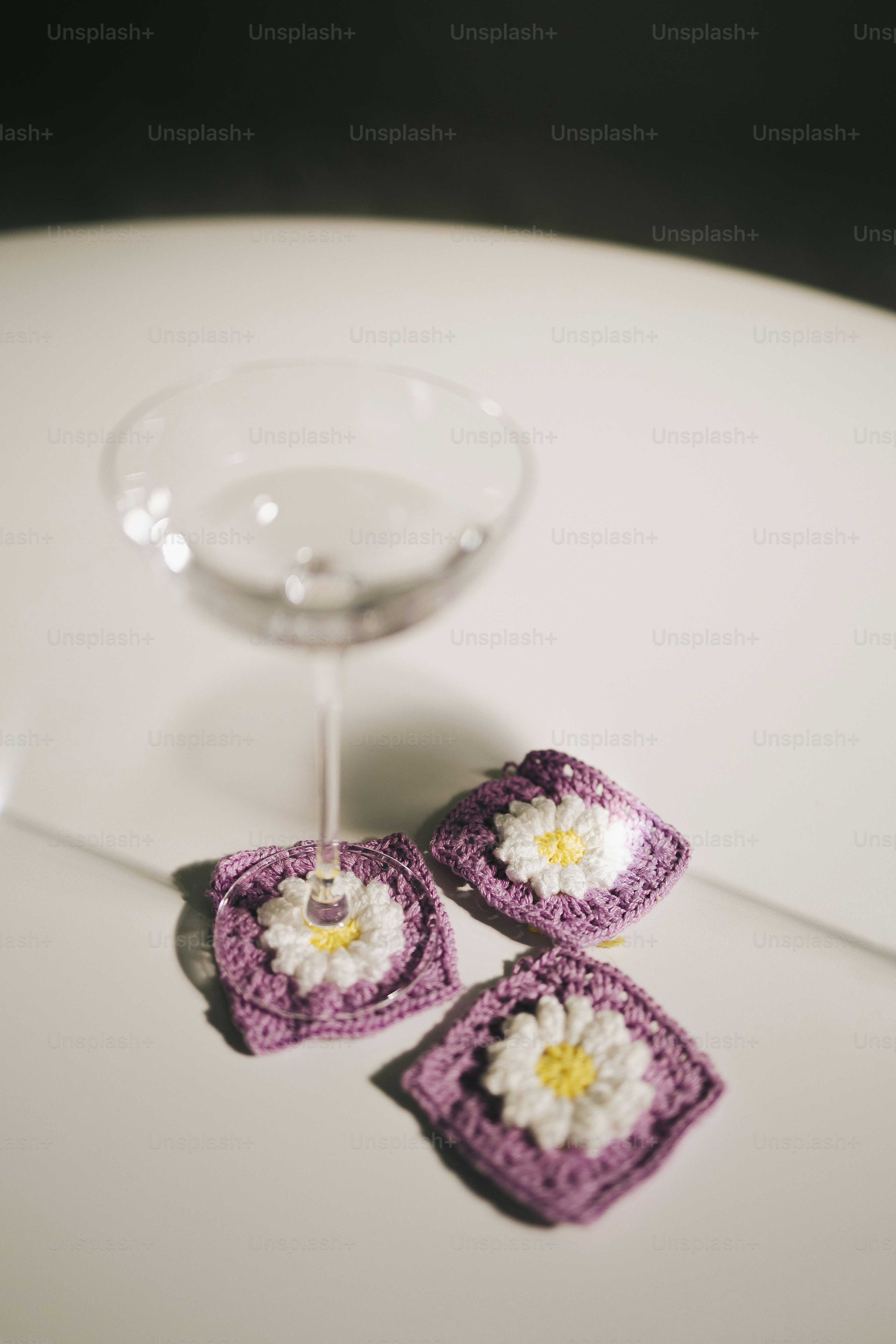 A champagne glass rests on crocheted daisy coasters.