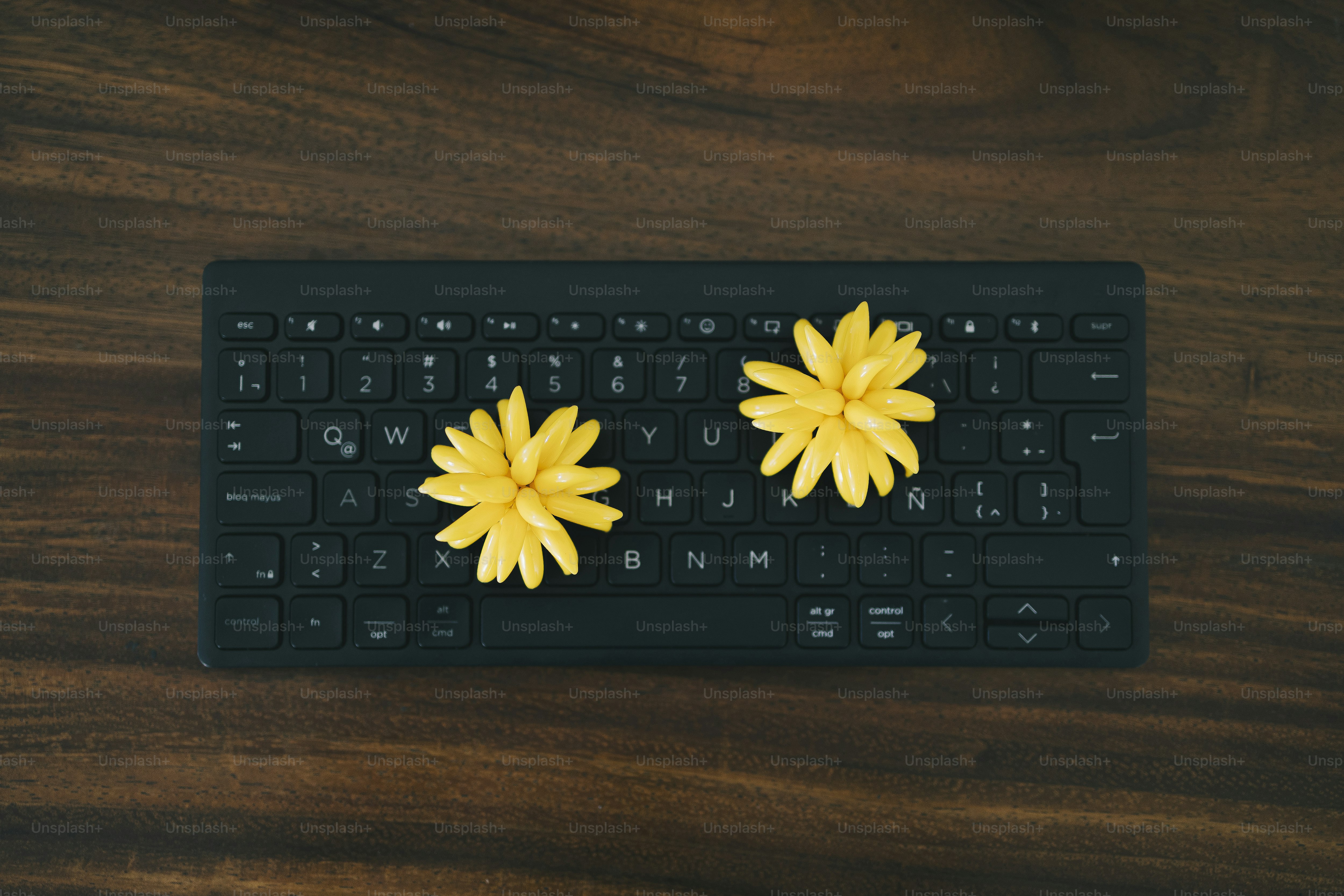 Flowers rest on a black keyboard on wood.
