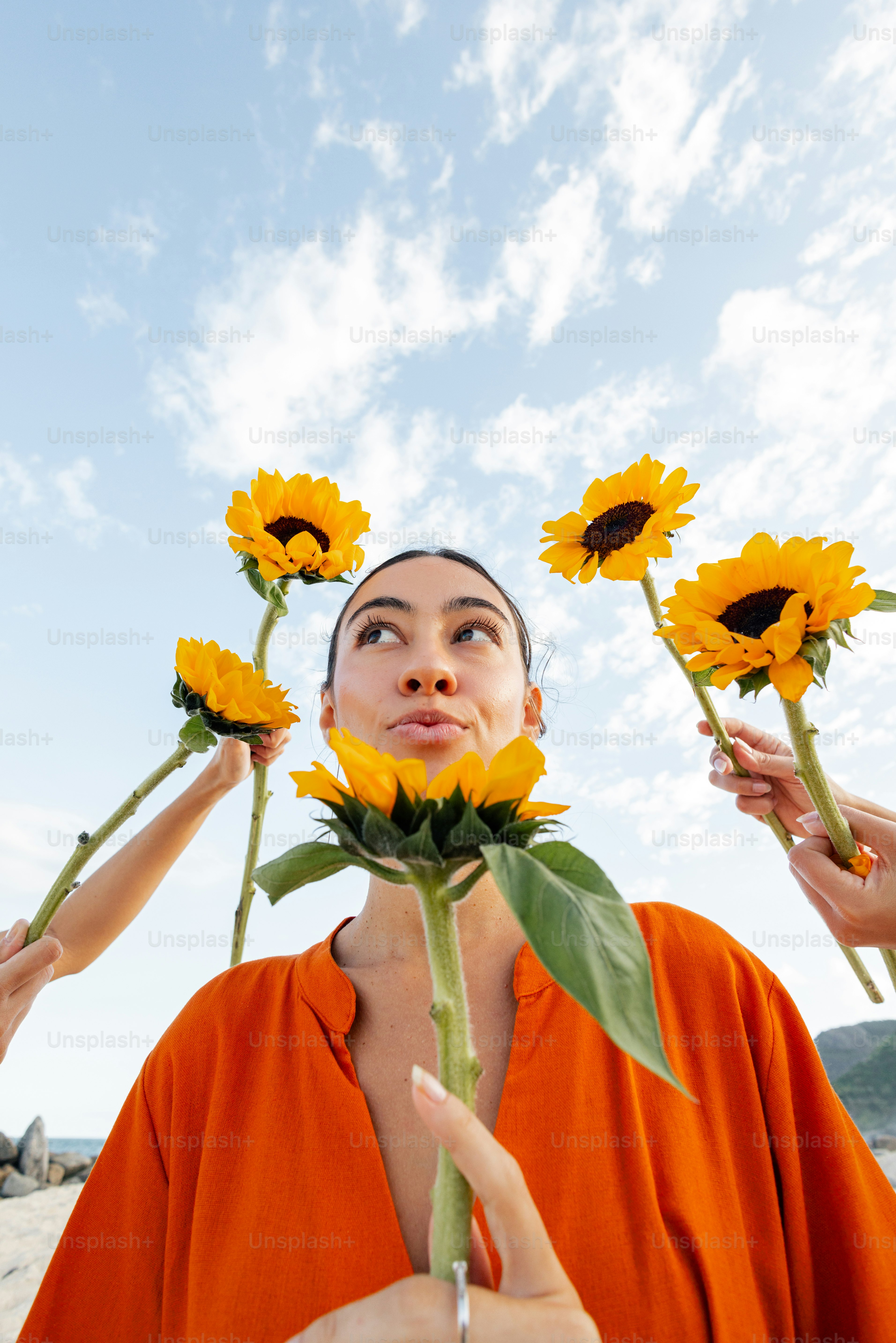 Femme pose avec des tournesols sur un ciel bleu vif.