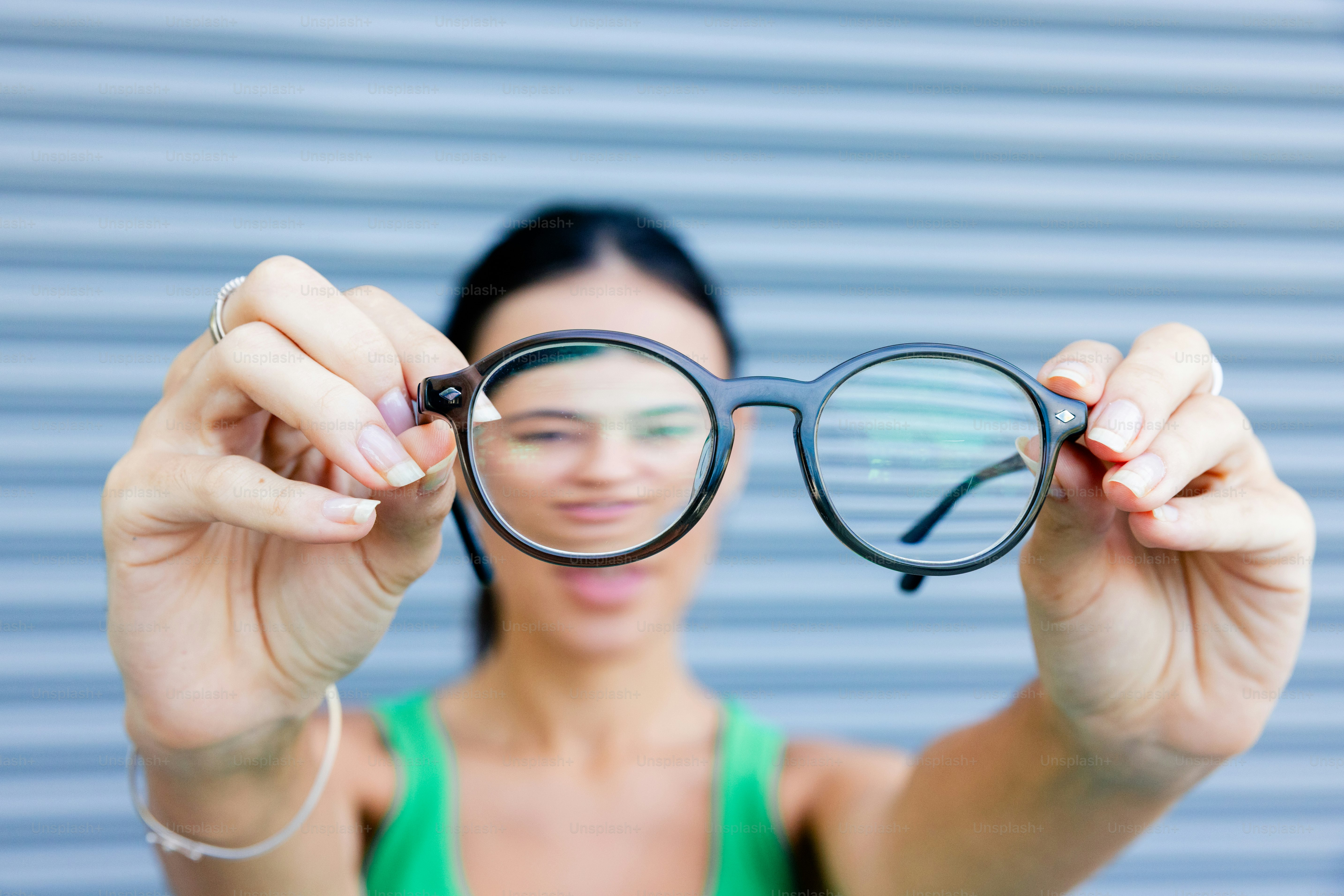 Woman is holding up a pair of glasses.