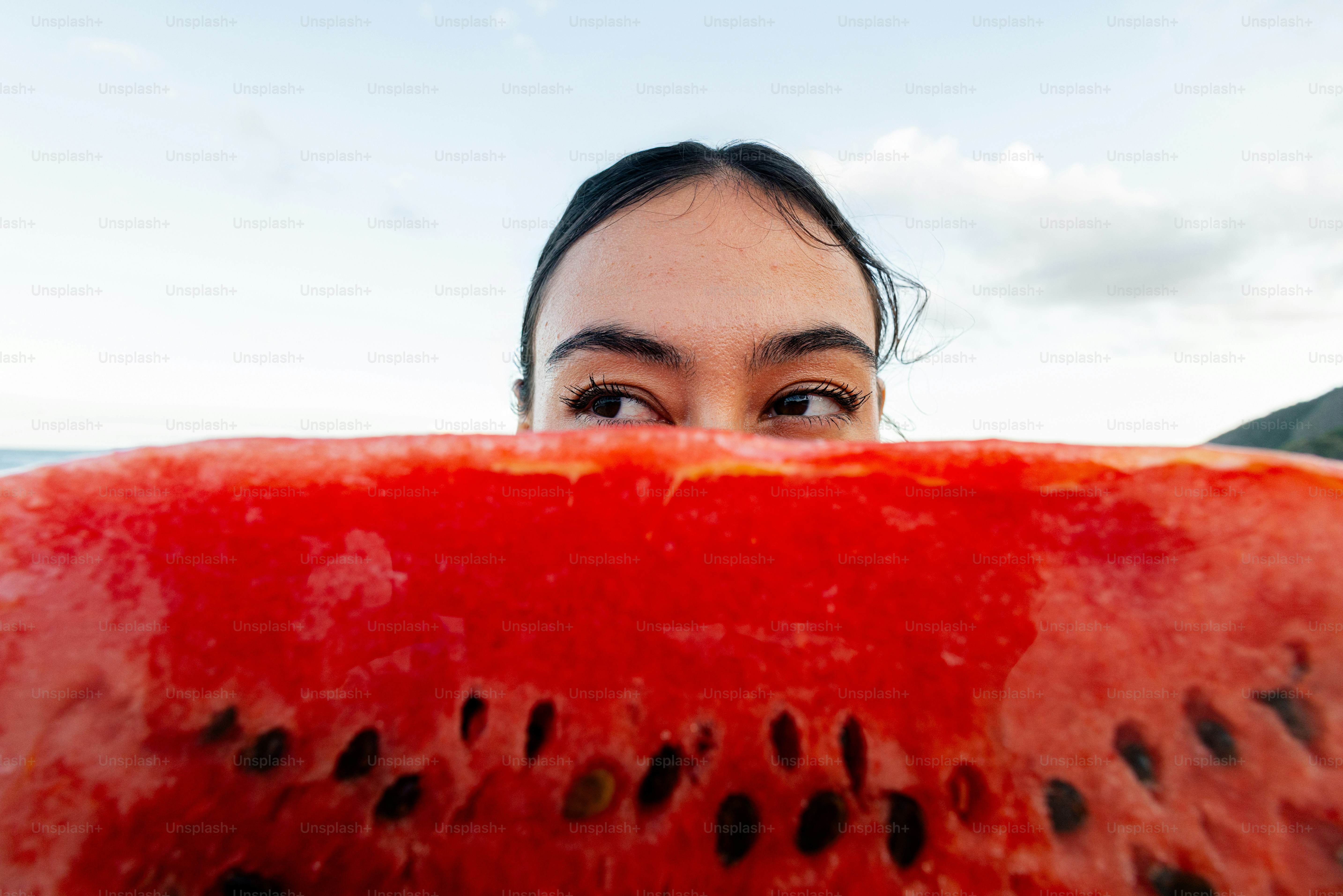 Woman peers over a large slice of watermelon.