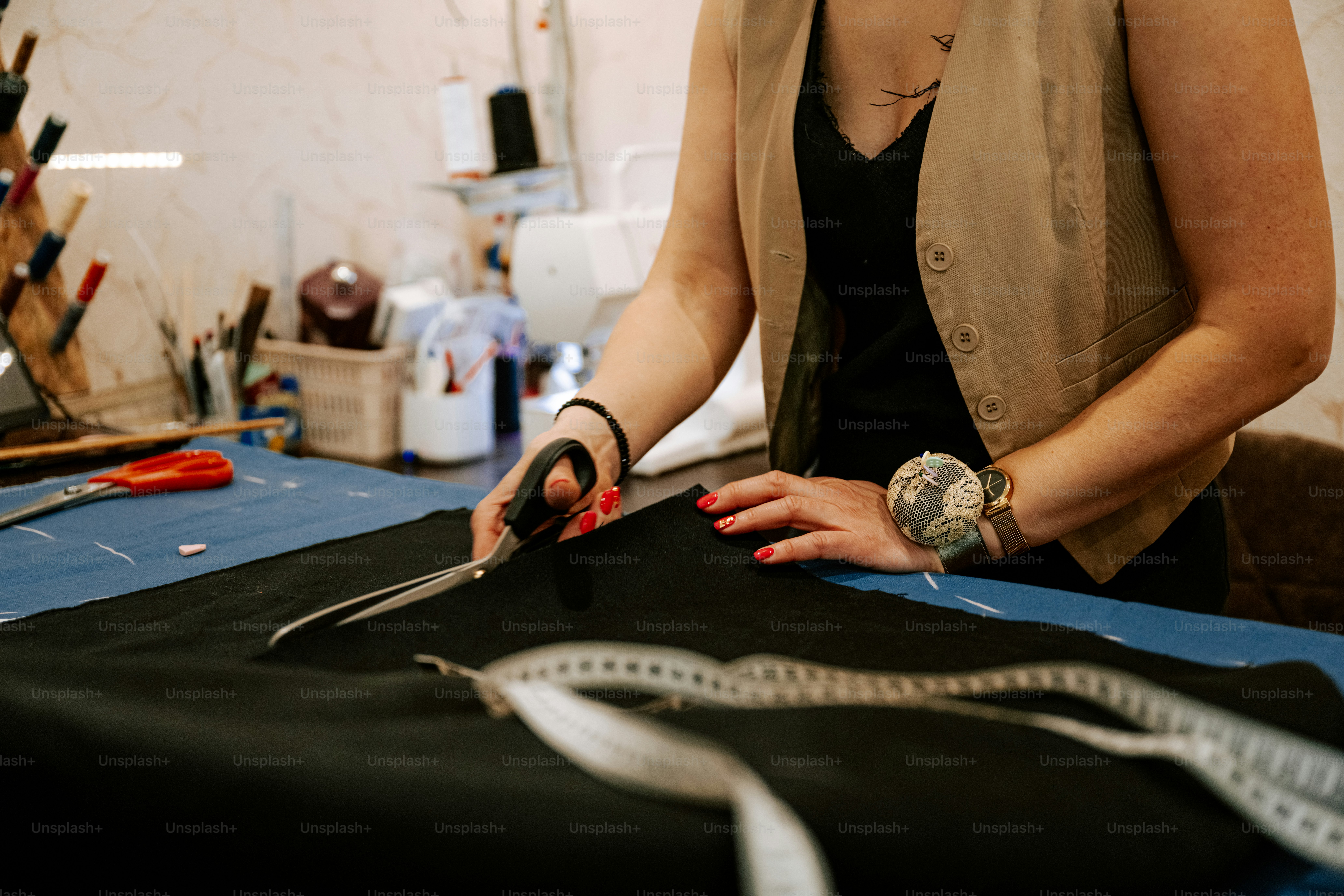 Une couturière coupe du tissu sur sa table de travail.