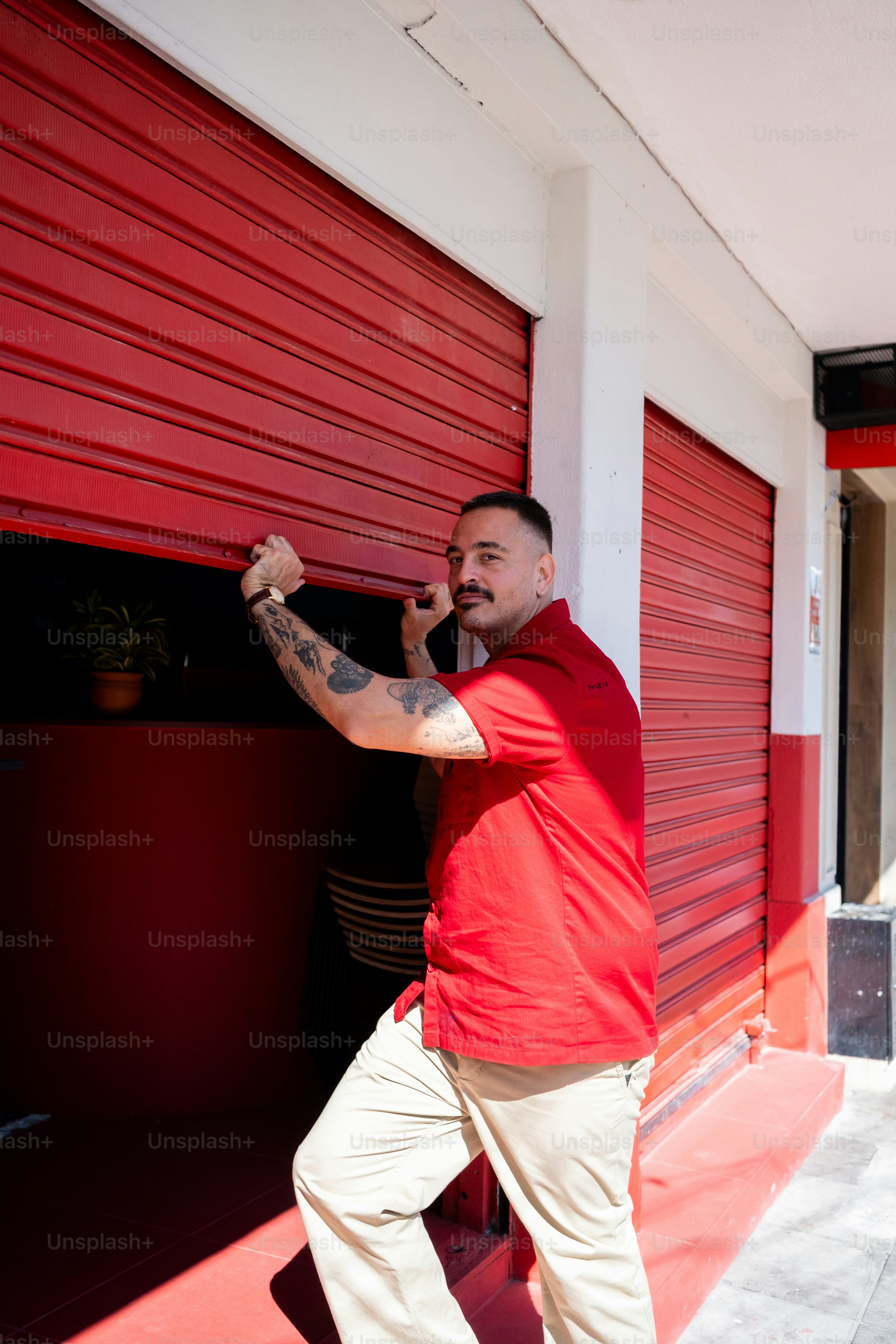 O homem abre uma porta vermelha do obturador