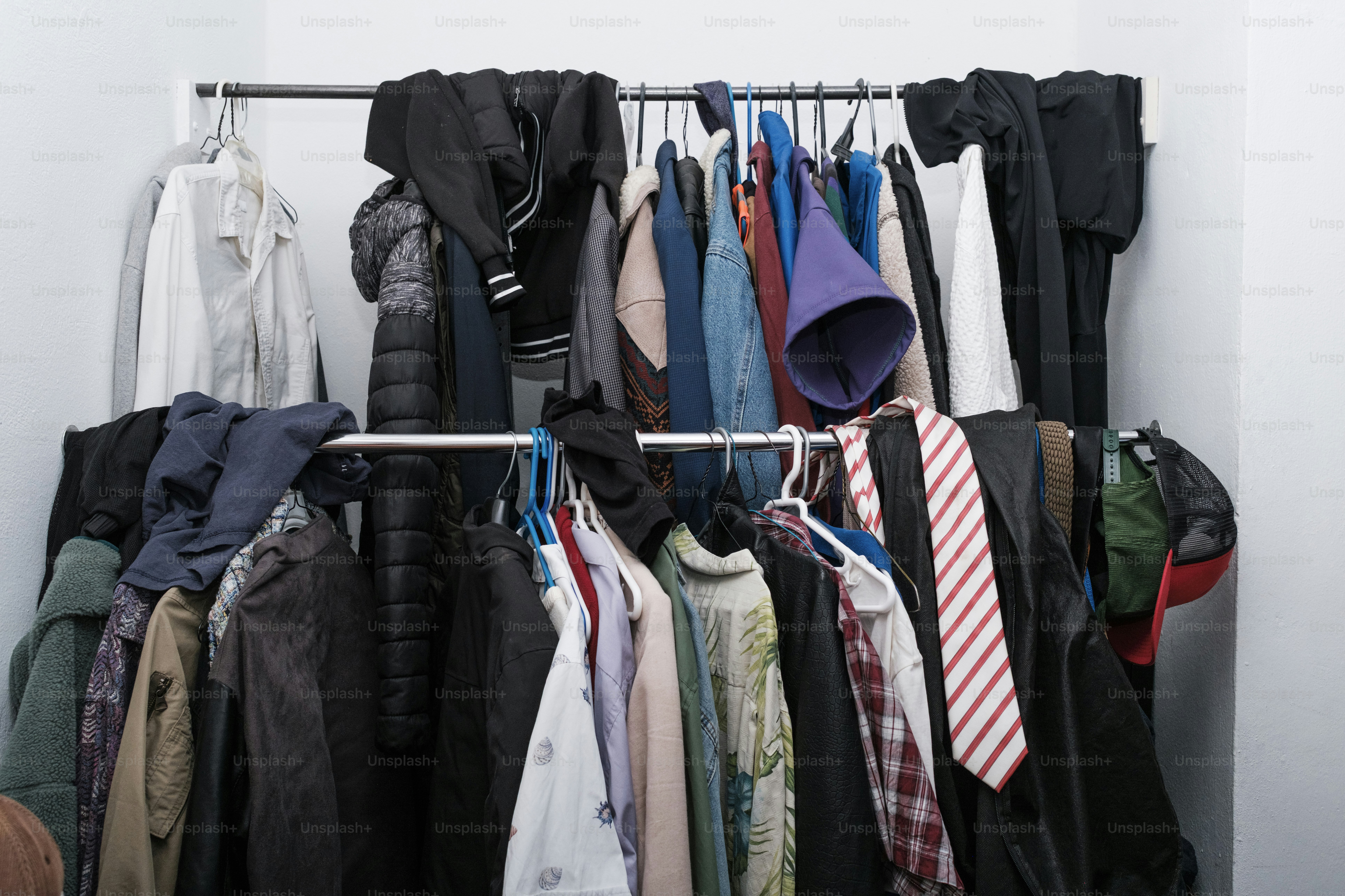 Clothes hang on a rack in a closet.