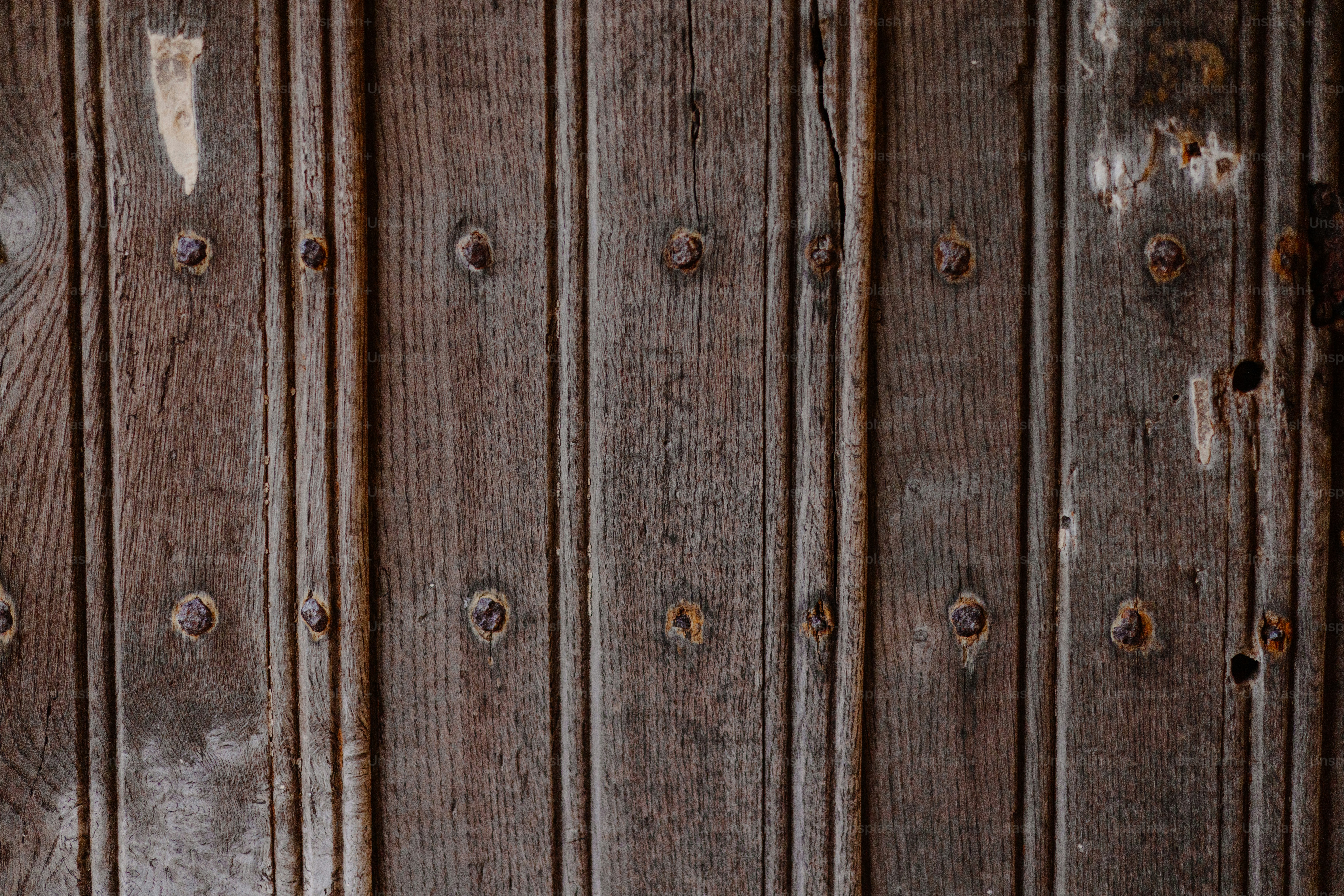 Old, wooden door with vertical planks and rivets.