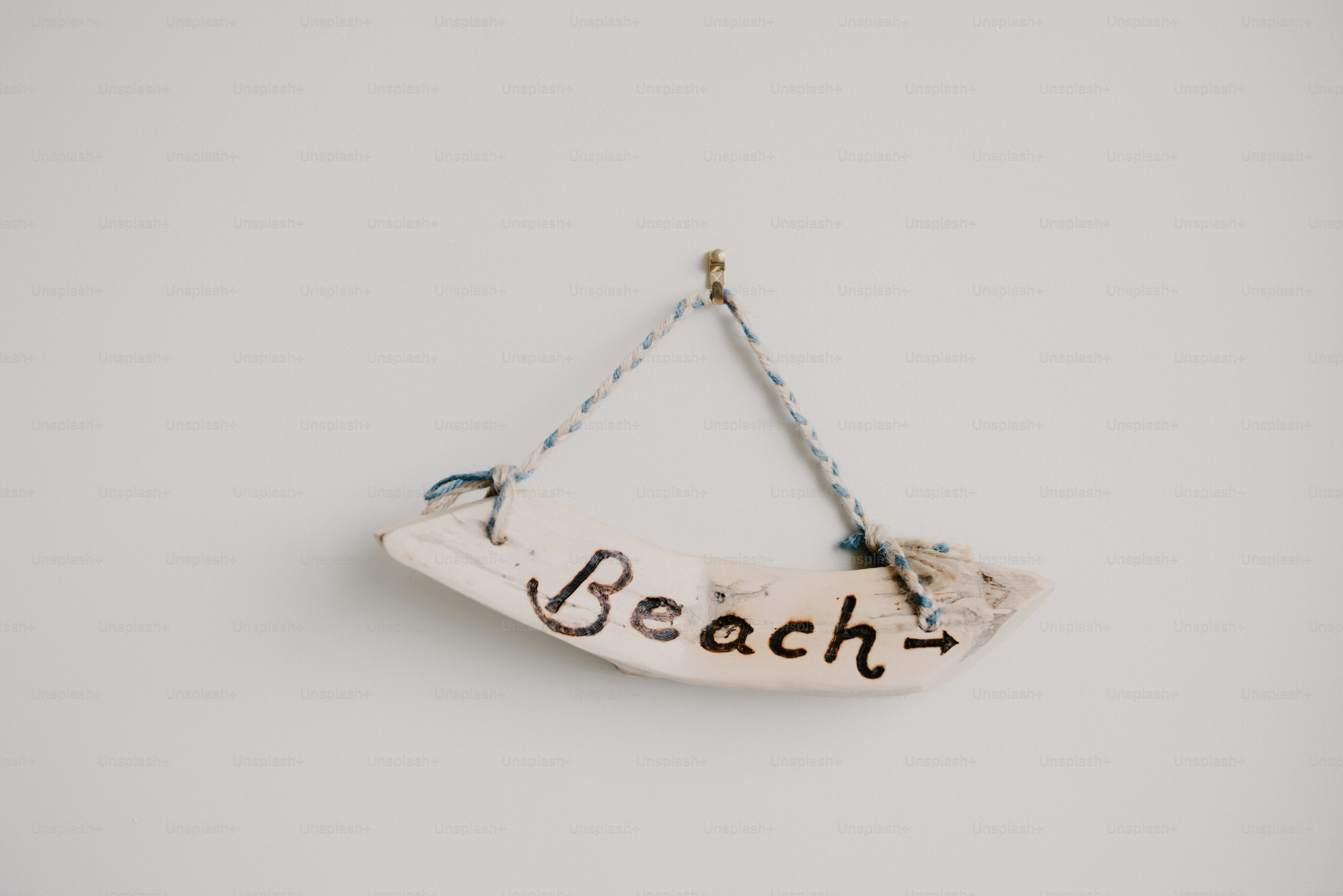 A "beach" sign hangs on a white wall.