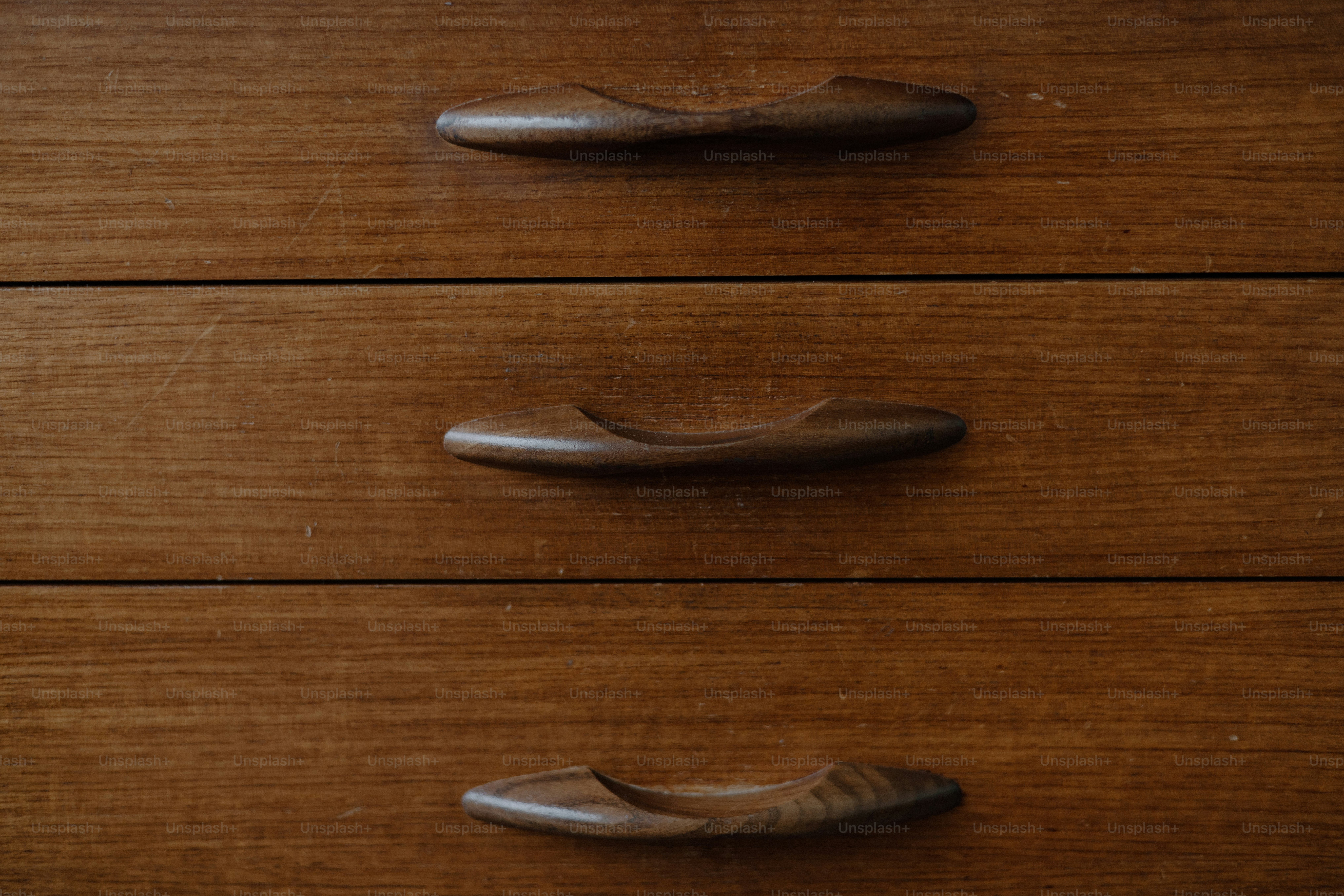 Three wooden drawers with unique handles.