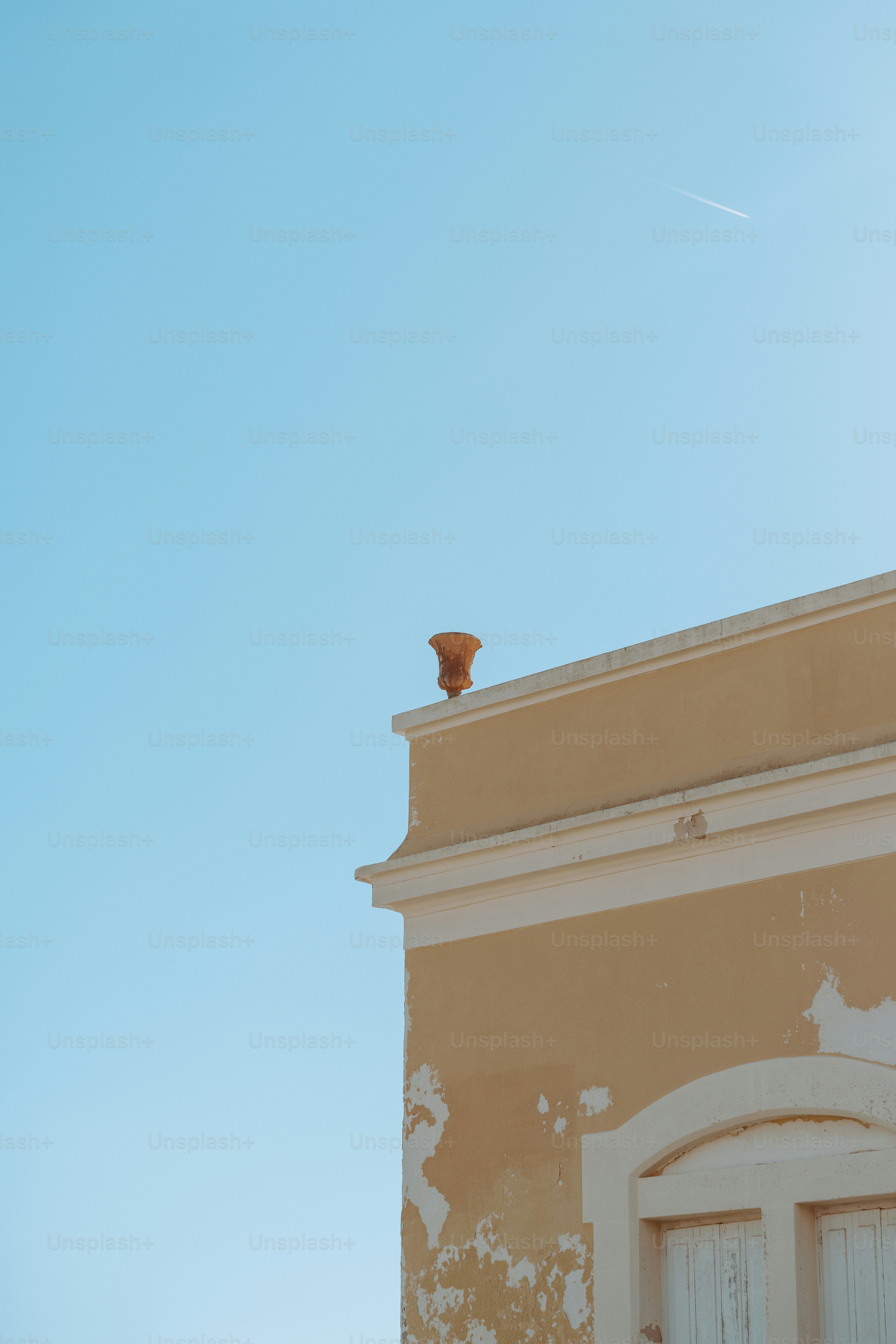 Building corner with a terracotta pot against blue sky.