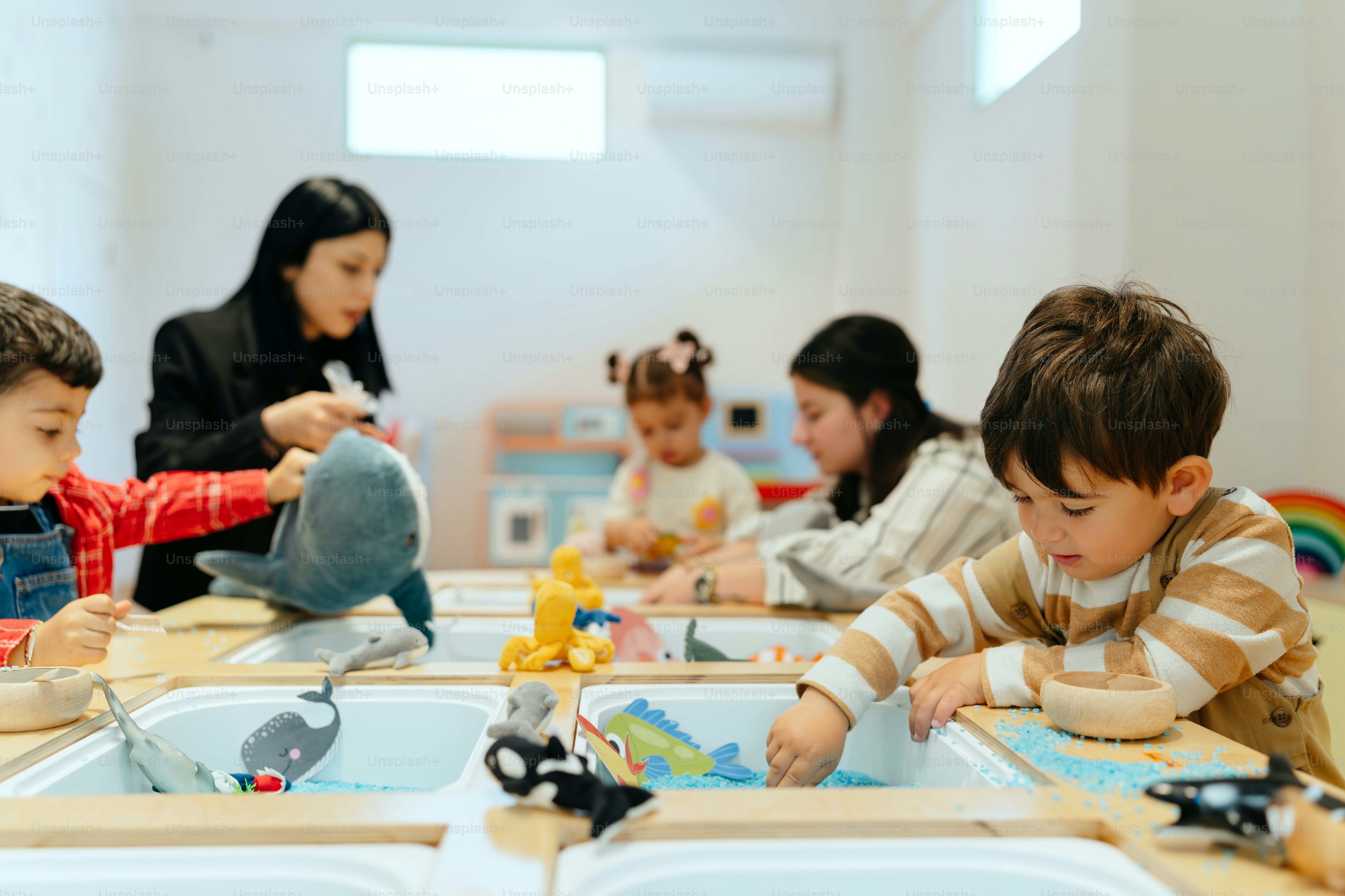 Children are playing with toys in a sensory bin.