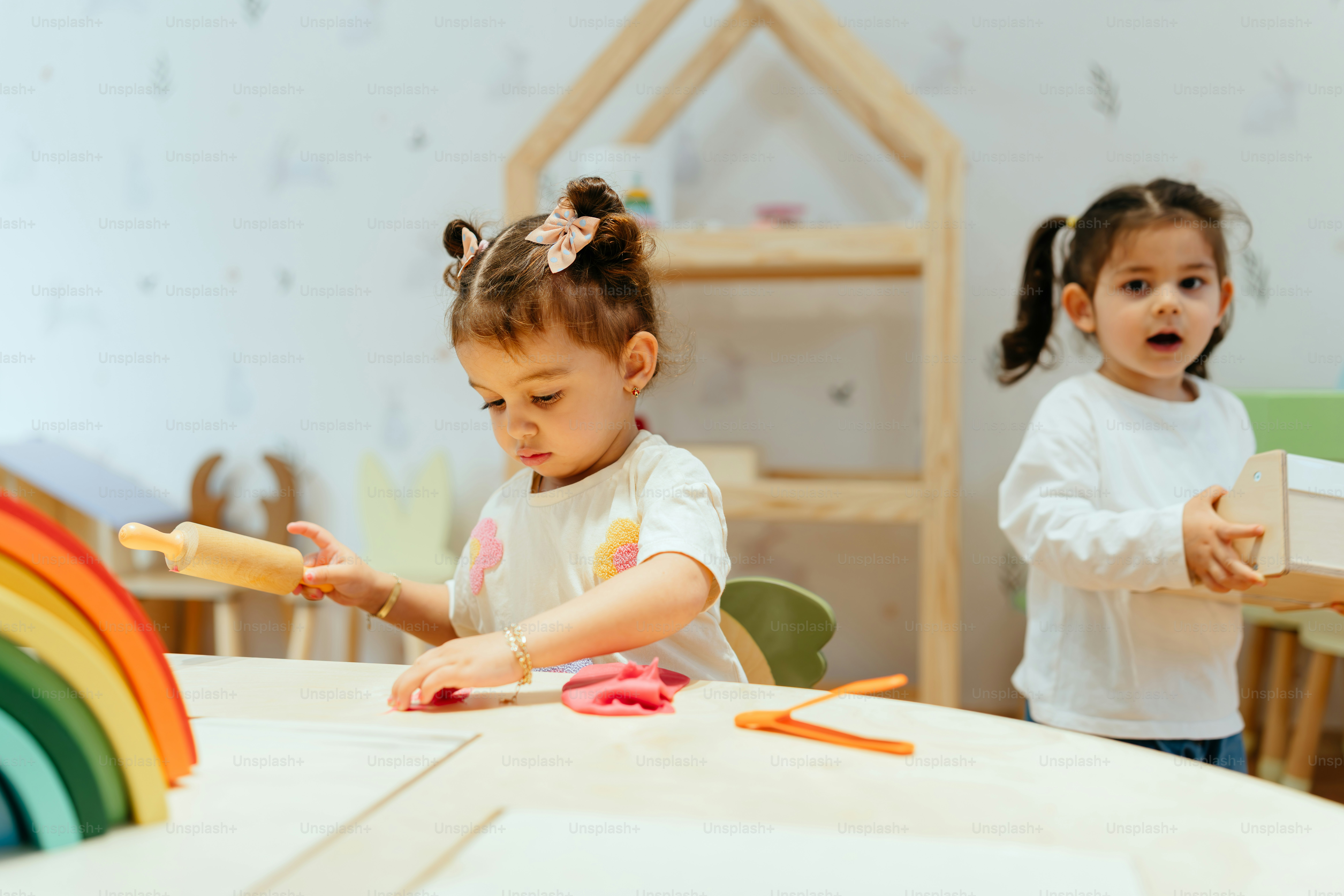 Two little girls play with playdough.