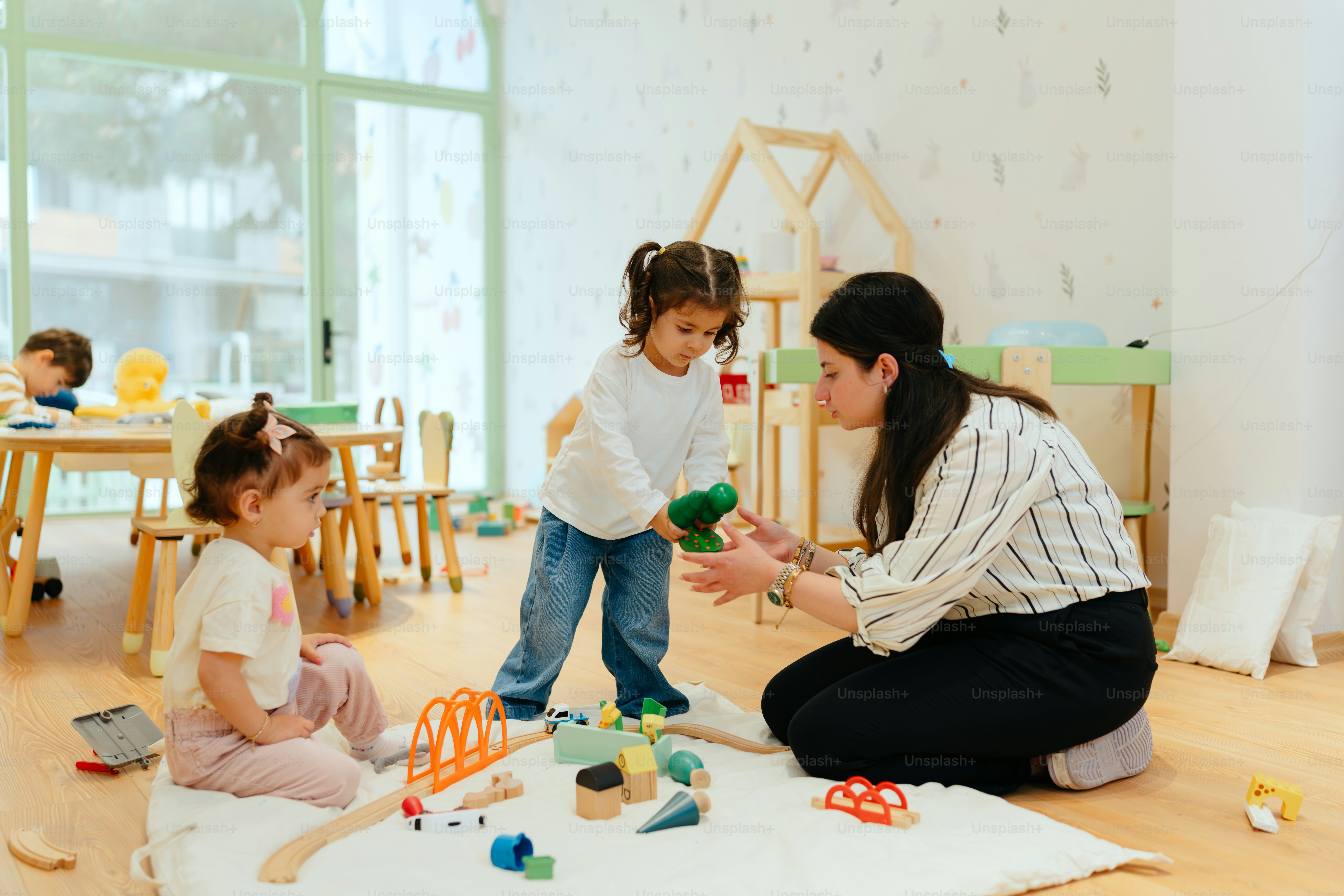 Children and a teacher play with toys indoors.
