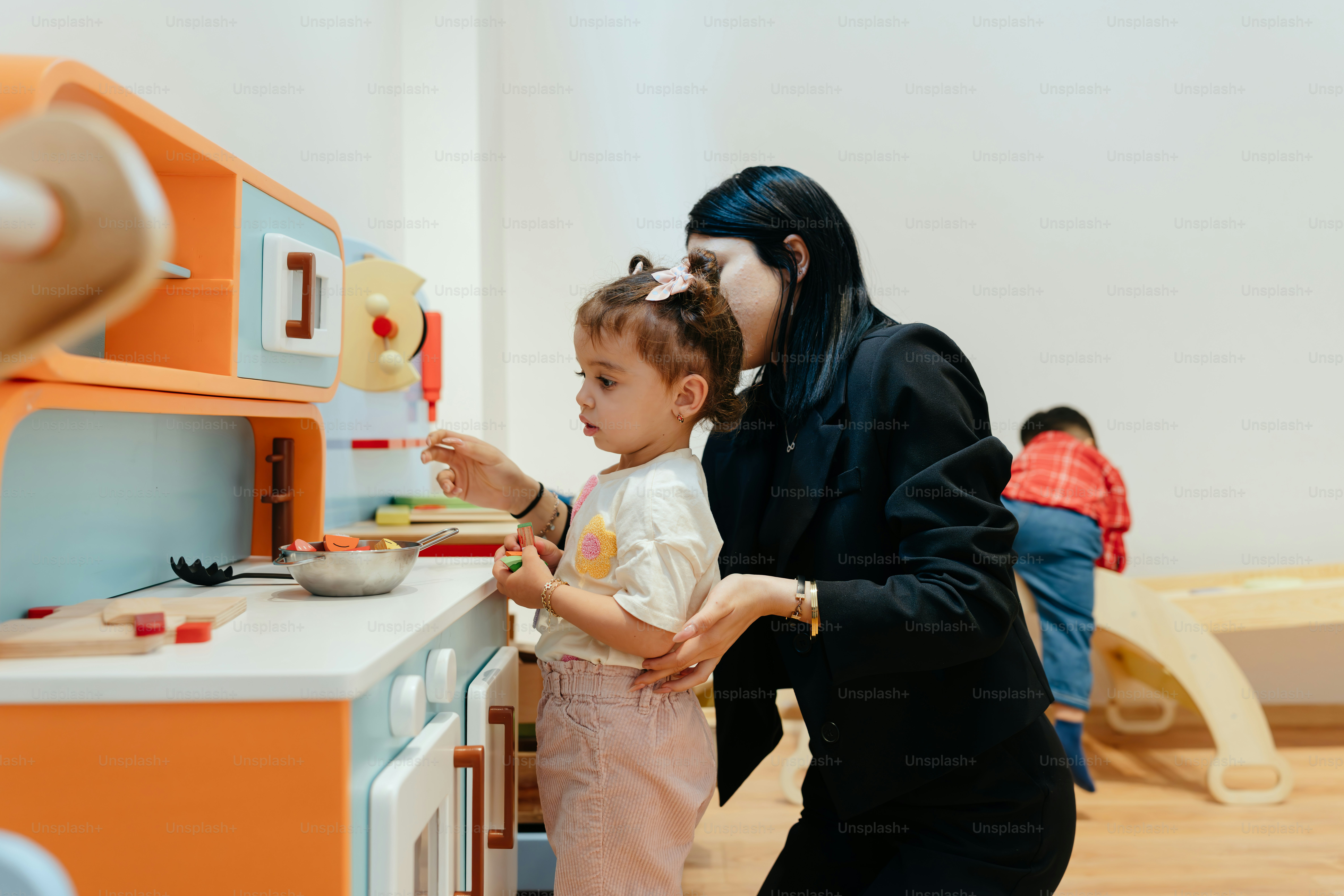 Um professor ajuda uma criança a cozinhar brinquedos.