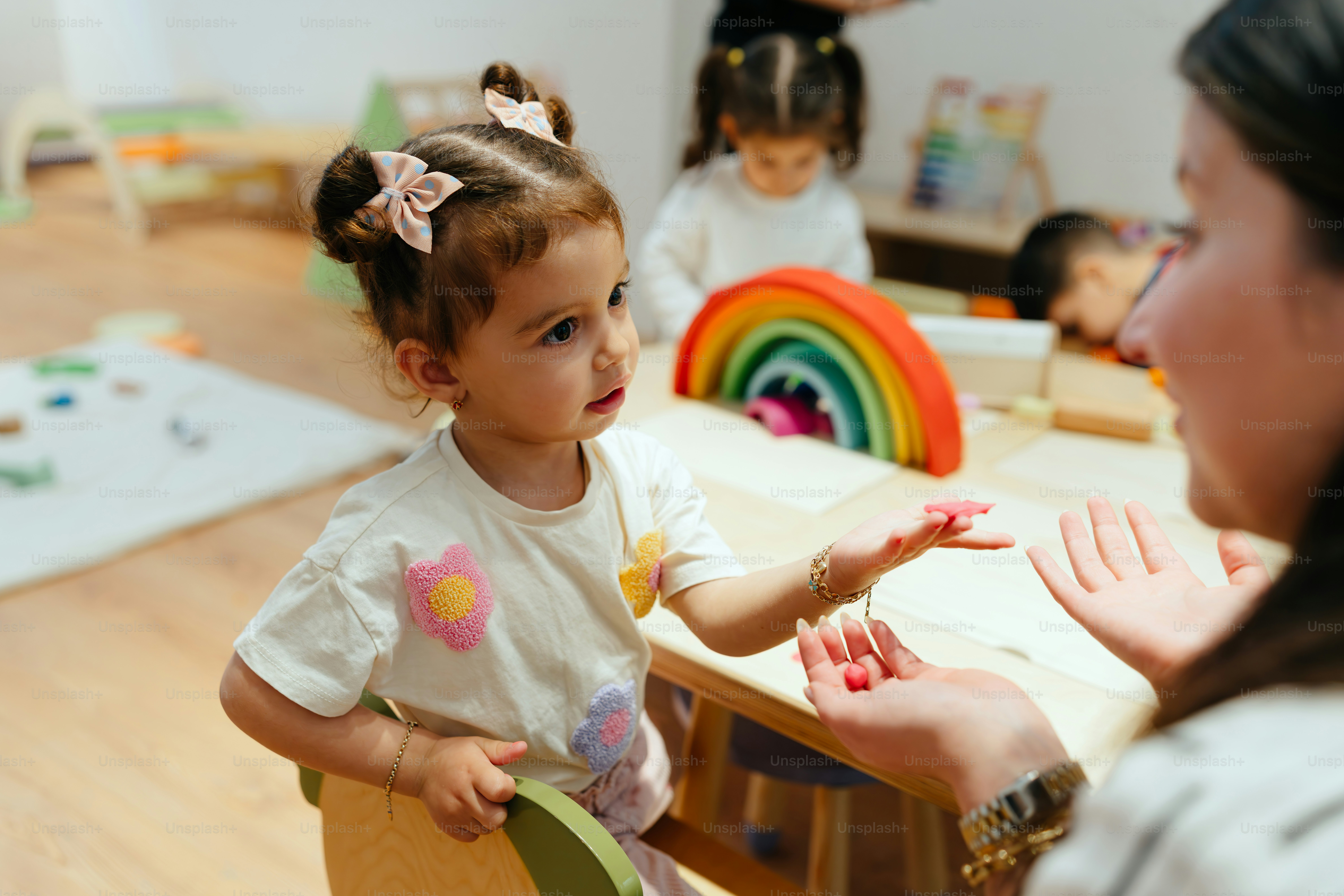 Das kleine Mädchen und die Lehrerin interagieren an einem Tisch.