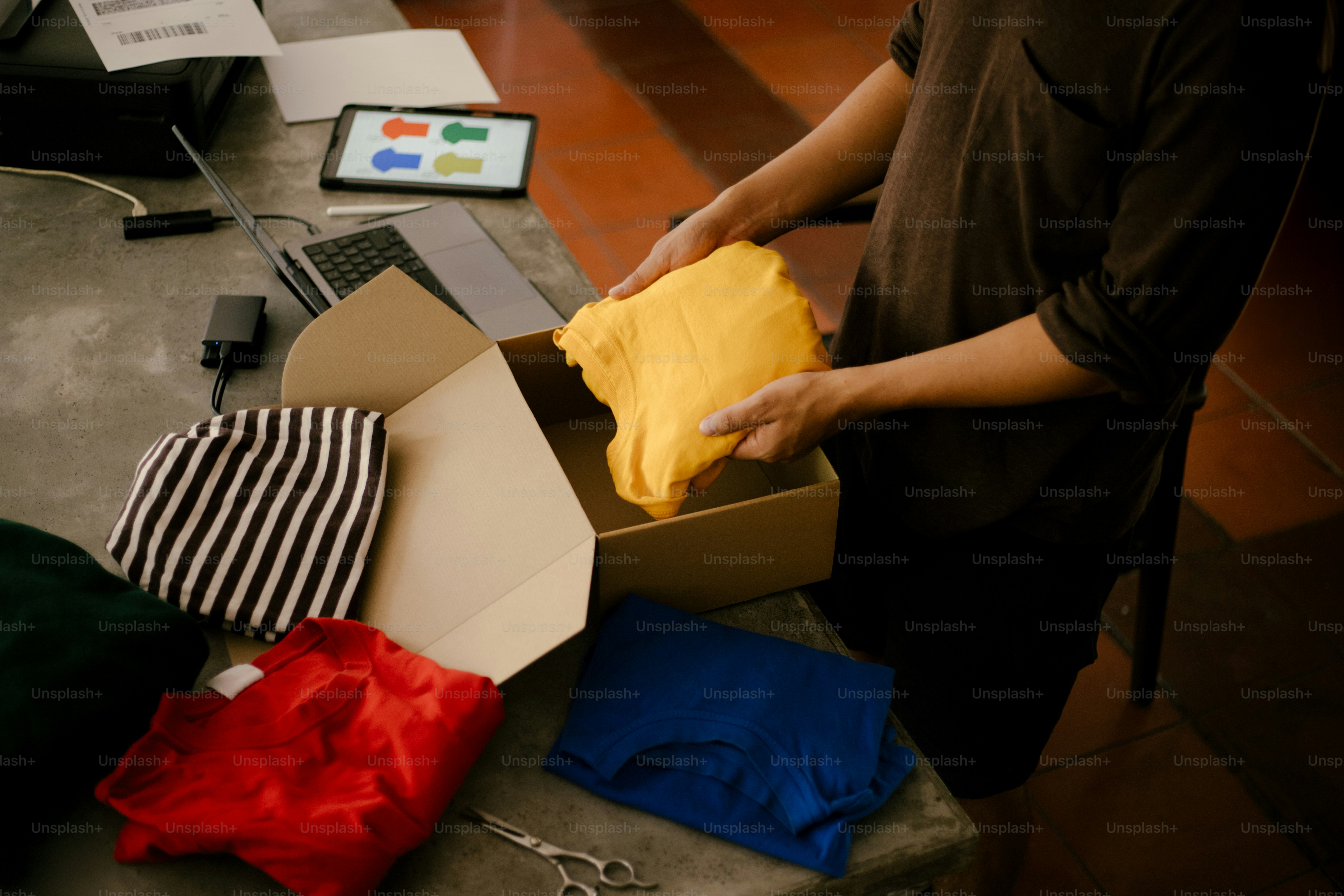 Someone is unpacking colorful clothes from a box.
