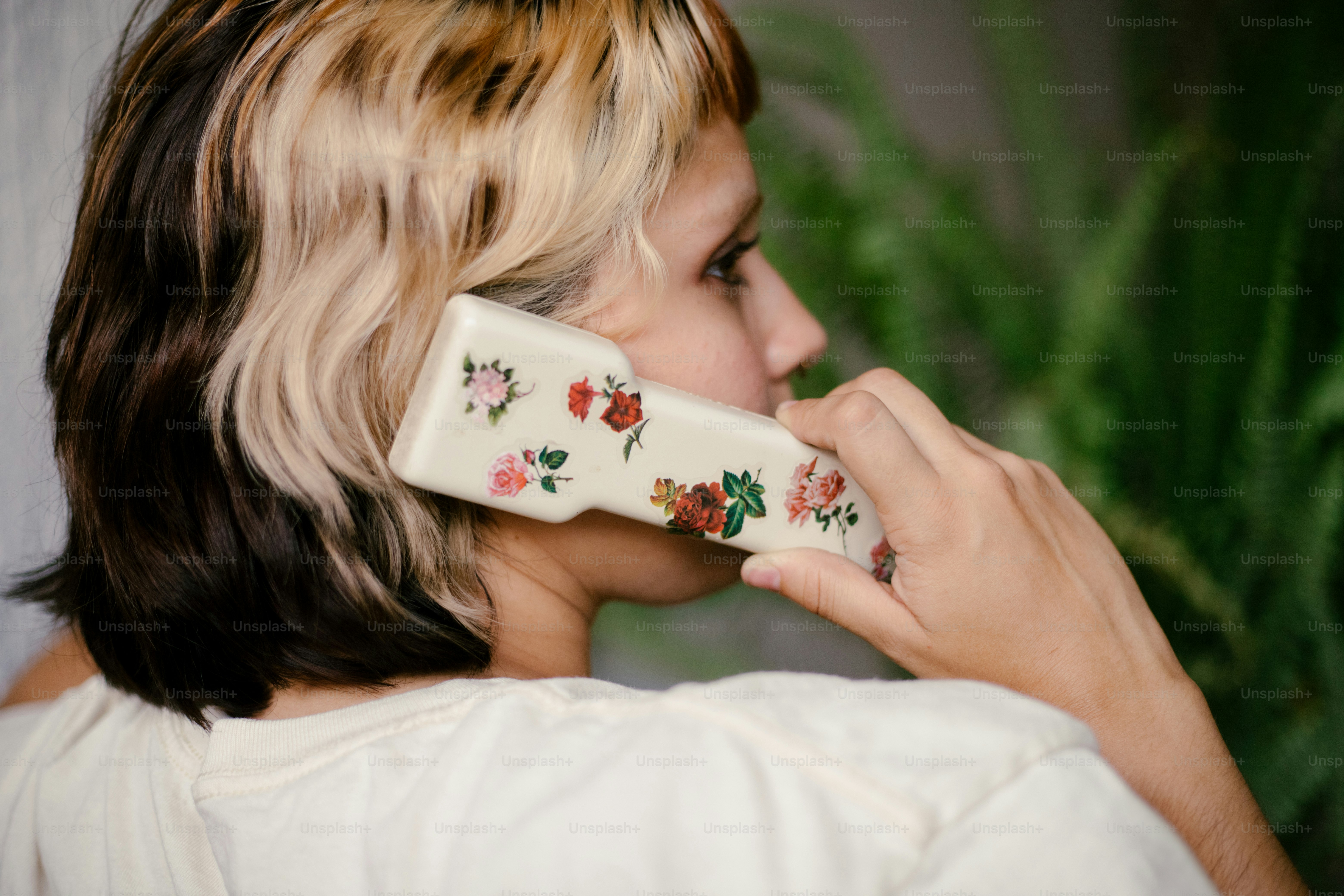 A woman talks on a phone with floral design.