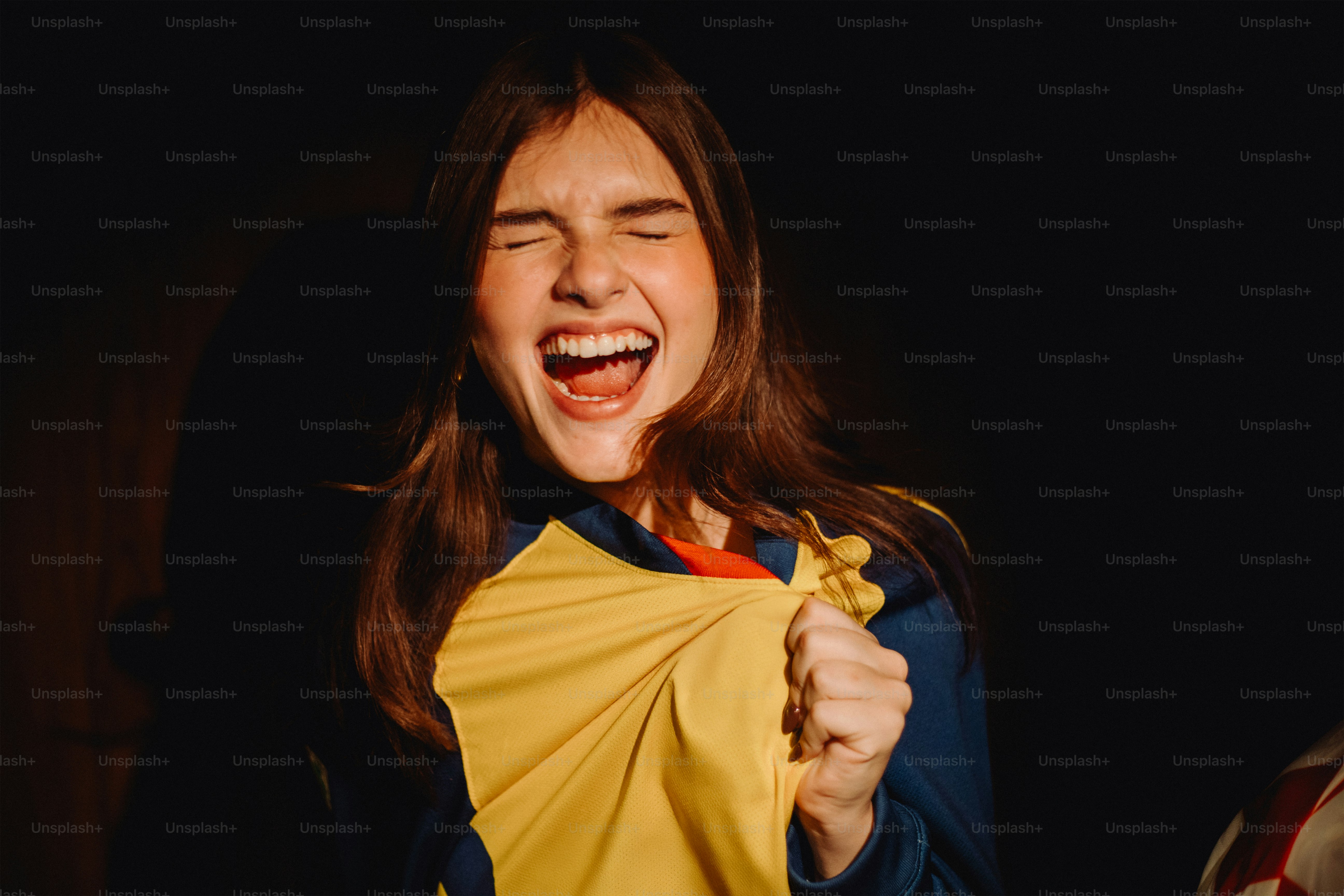 Woman laughs with eyes closed, holding yellow fabric.