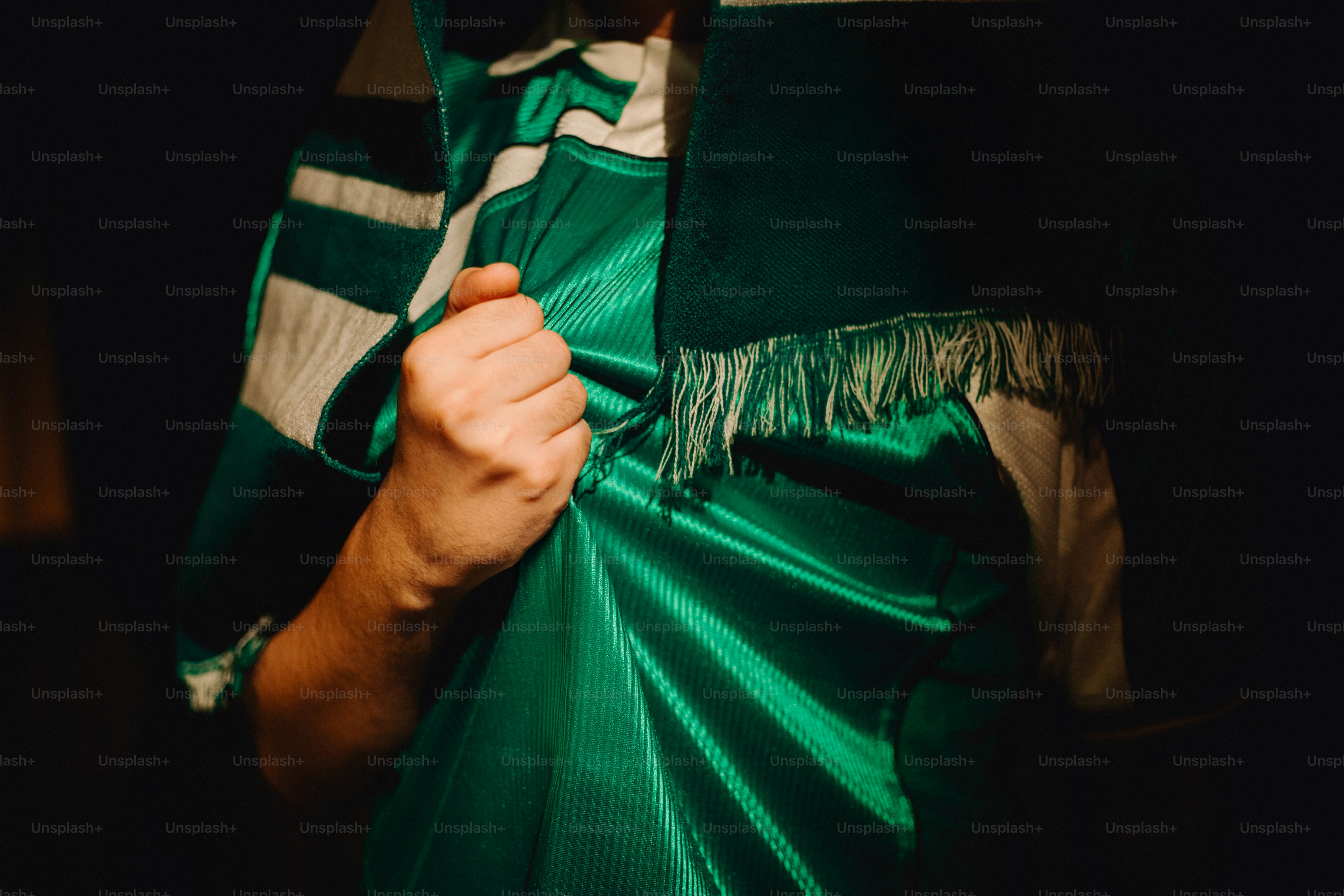 A person holds up a green and white scarf.