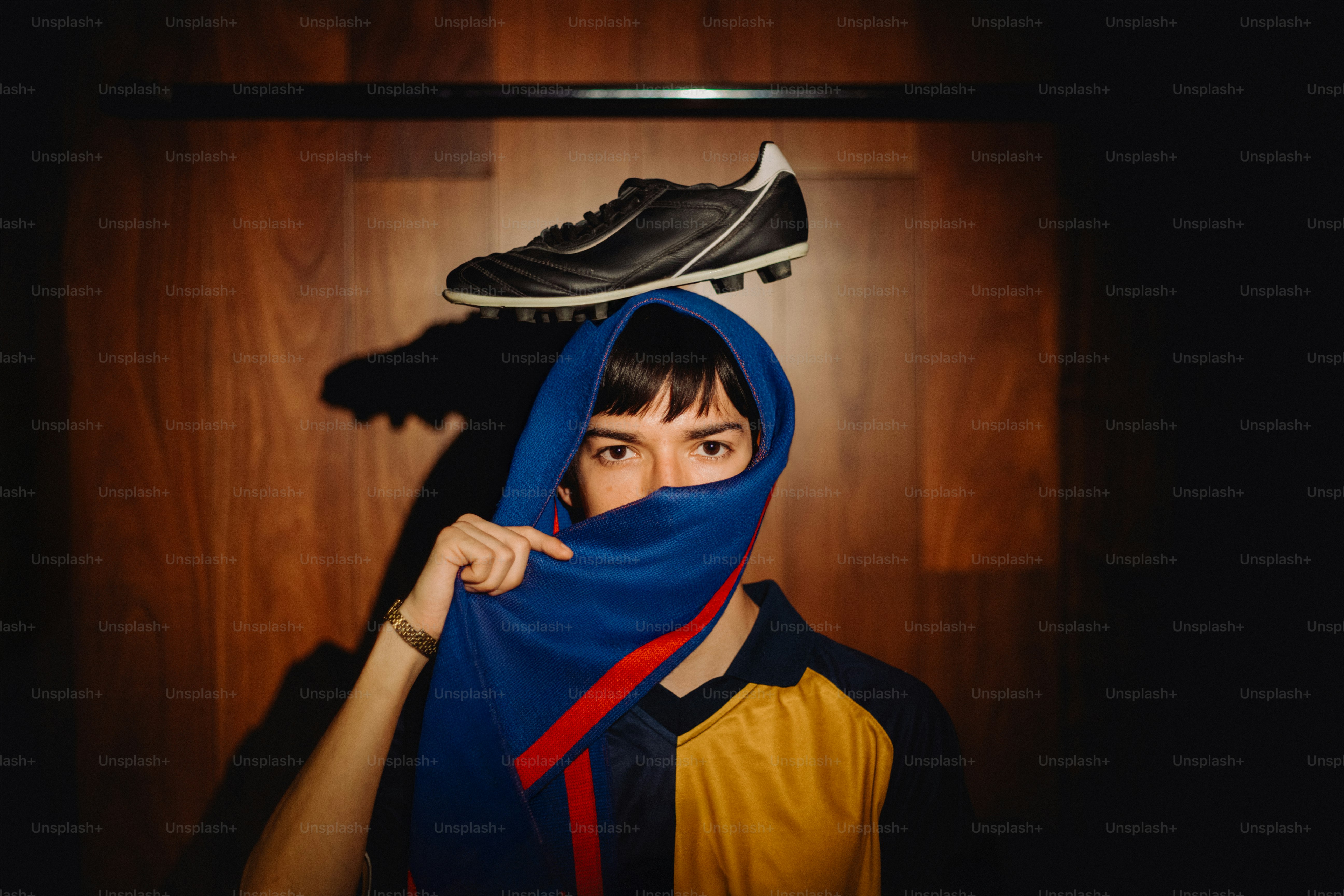 La personne tient un maillot avec une chaussure de football sur la tête.