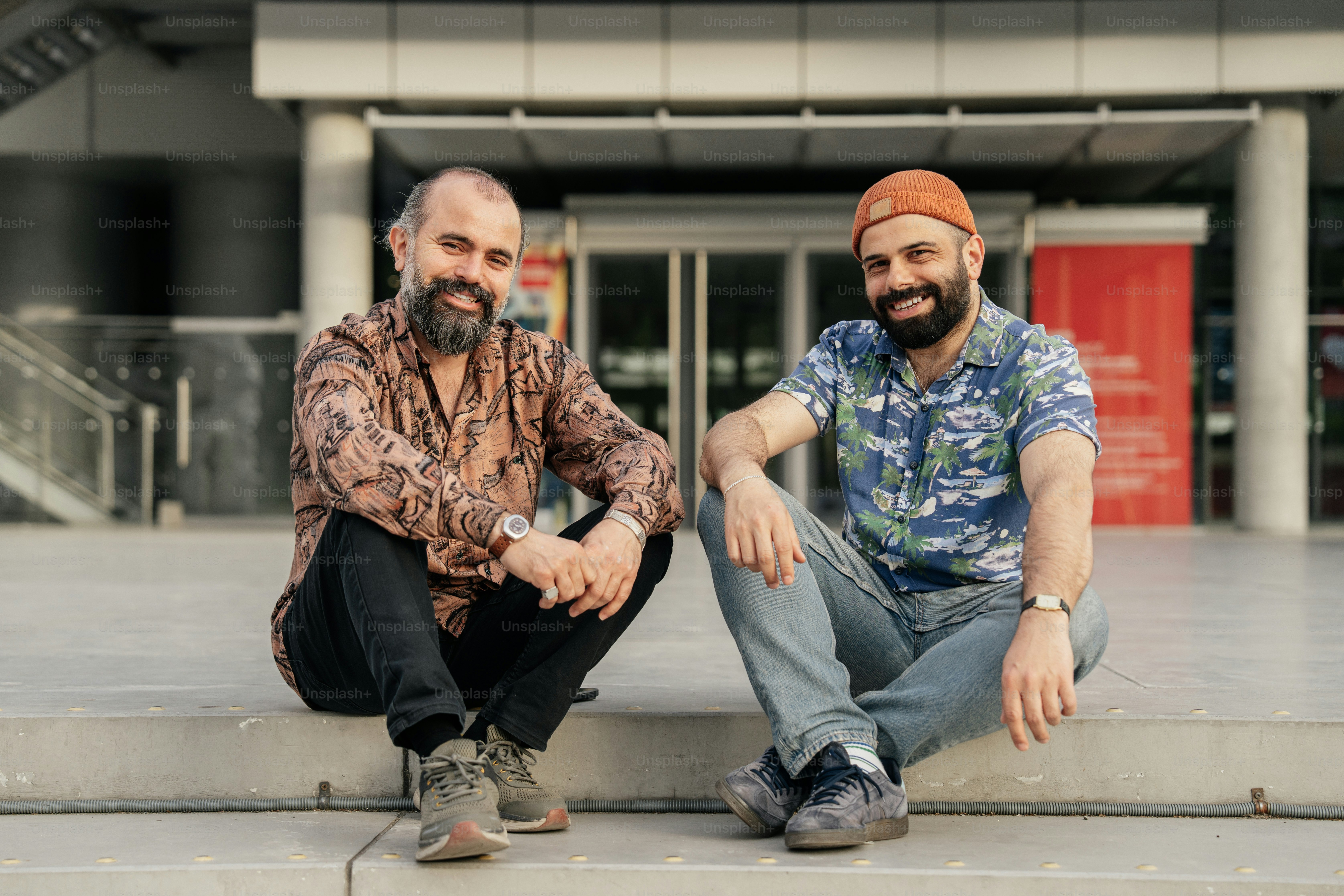 Two men sit together outside a building.