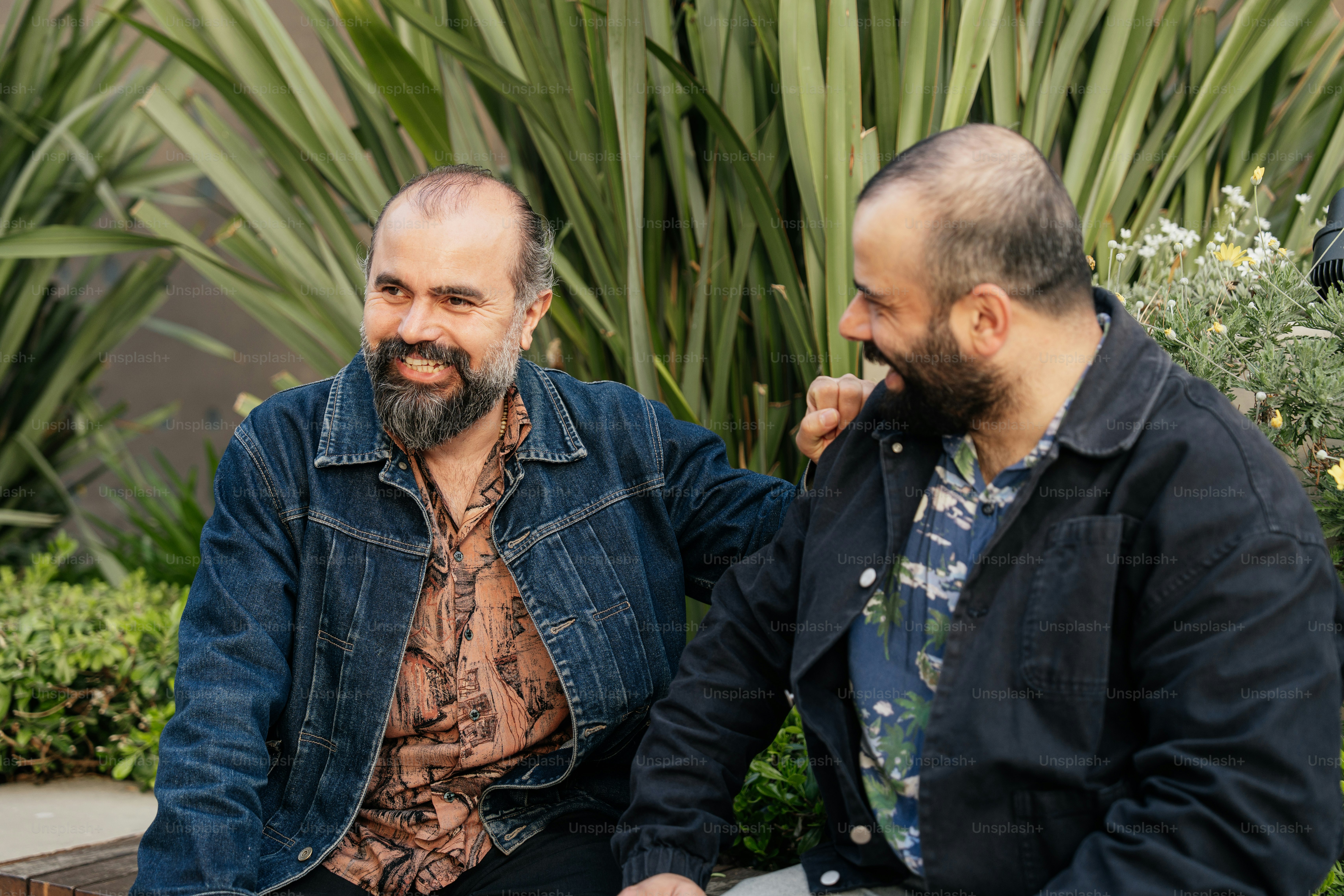 Two men laugh and smile together outside.