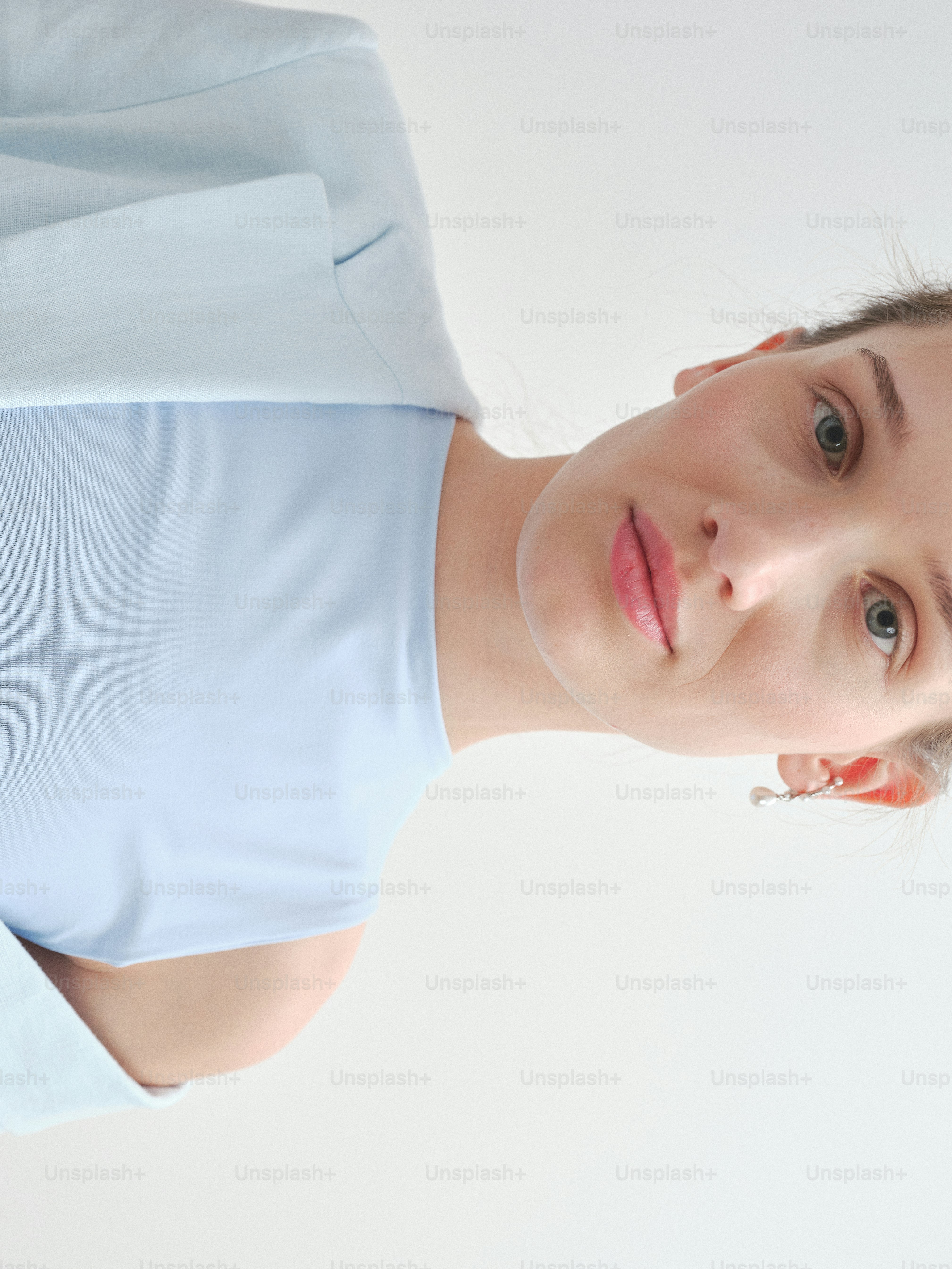 Eine Frau in hellblauer Kleidung starrt vor sich hin.