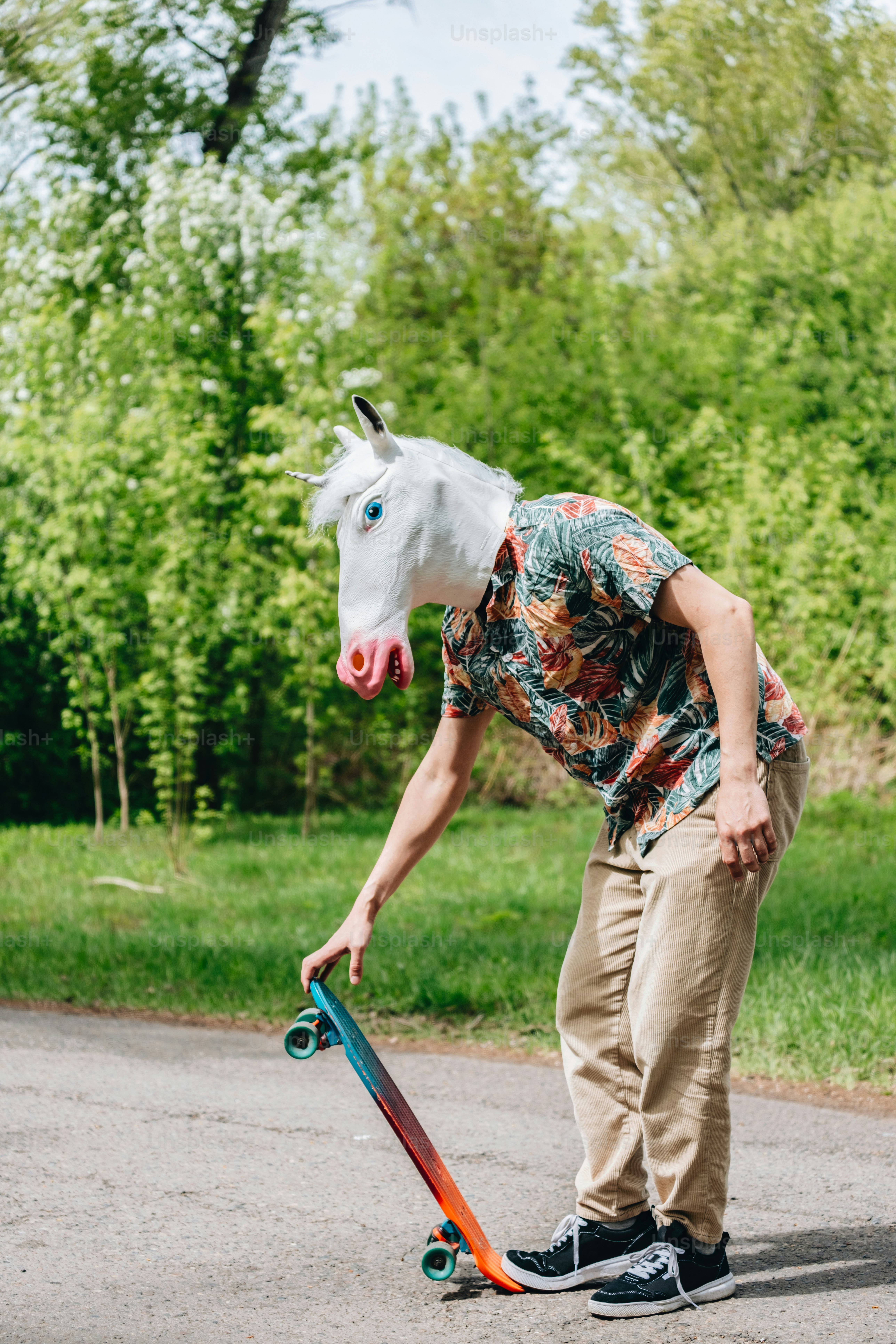 A person wearing a unicorn mask prepares to skateboard