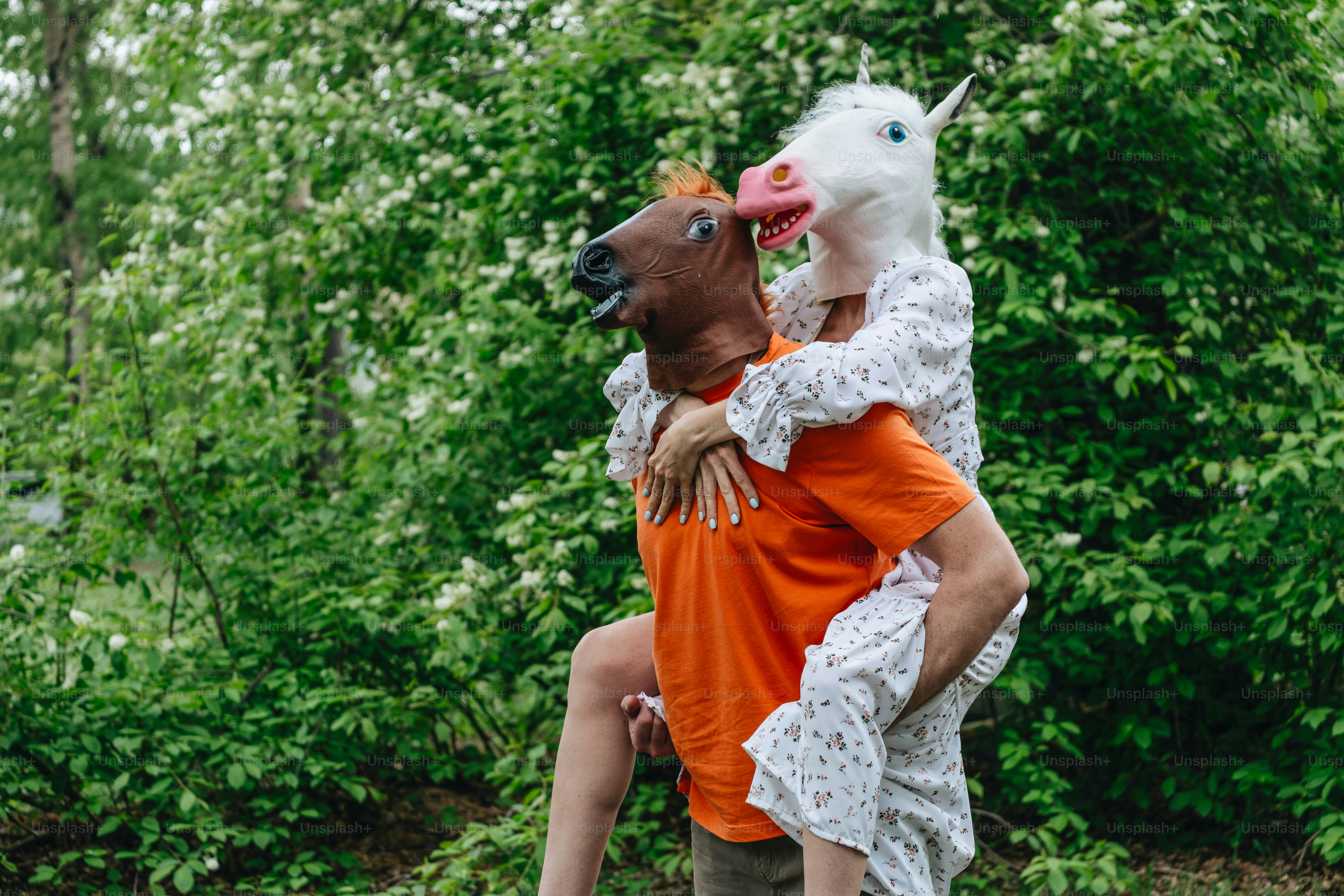 Une personne en porte une autre, toutes deux portant des masques de cheval.