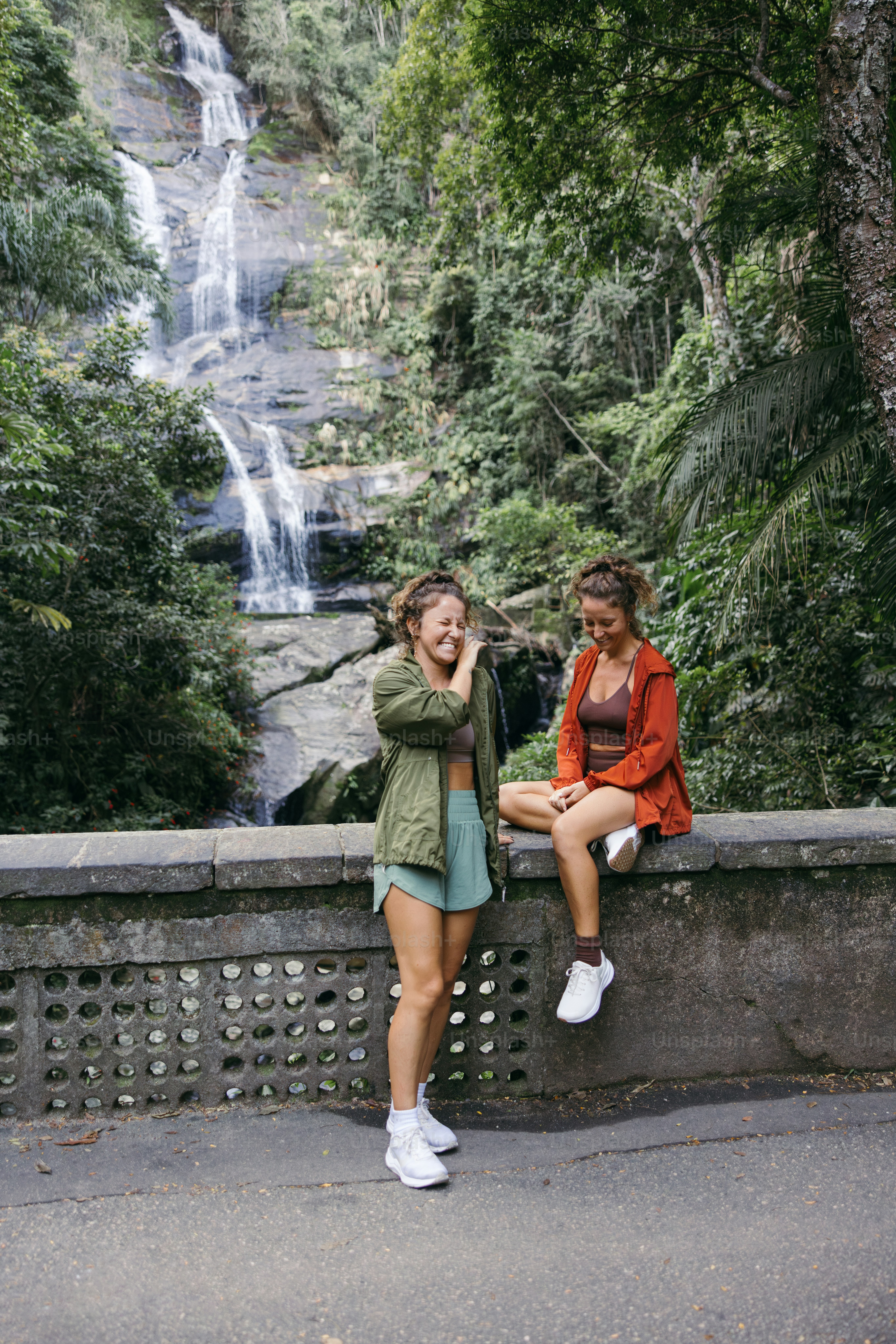Two friends laughing by a beautiful waterfall.