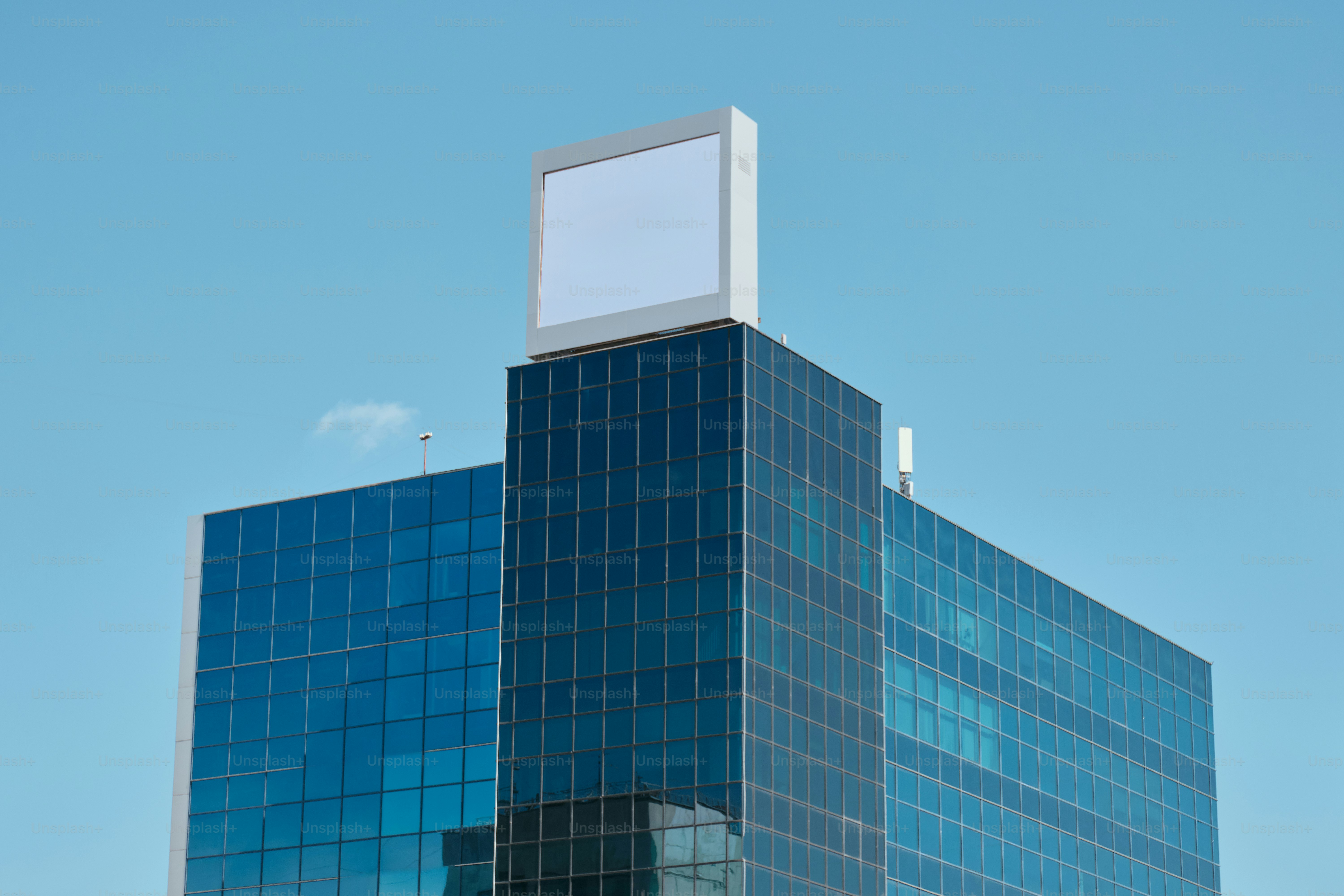 Modern glass building with blank sign on top.